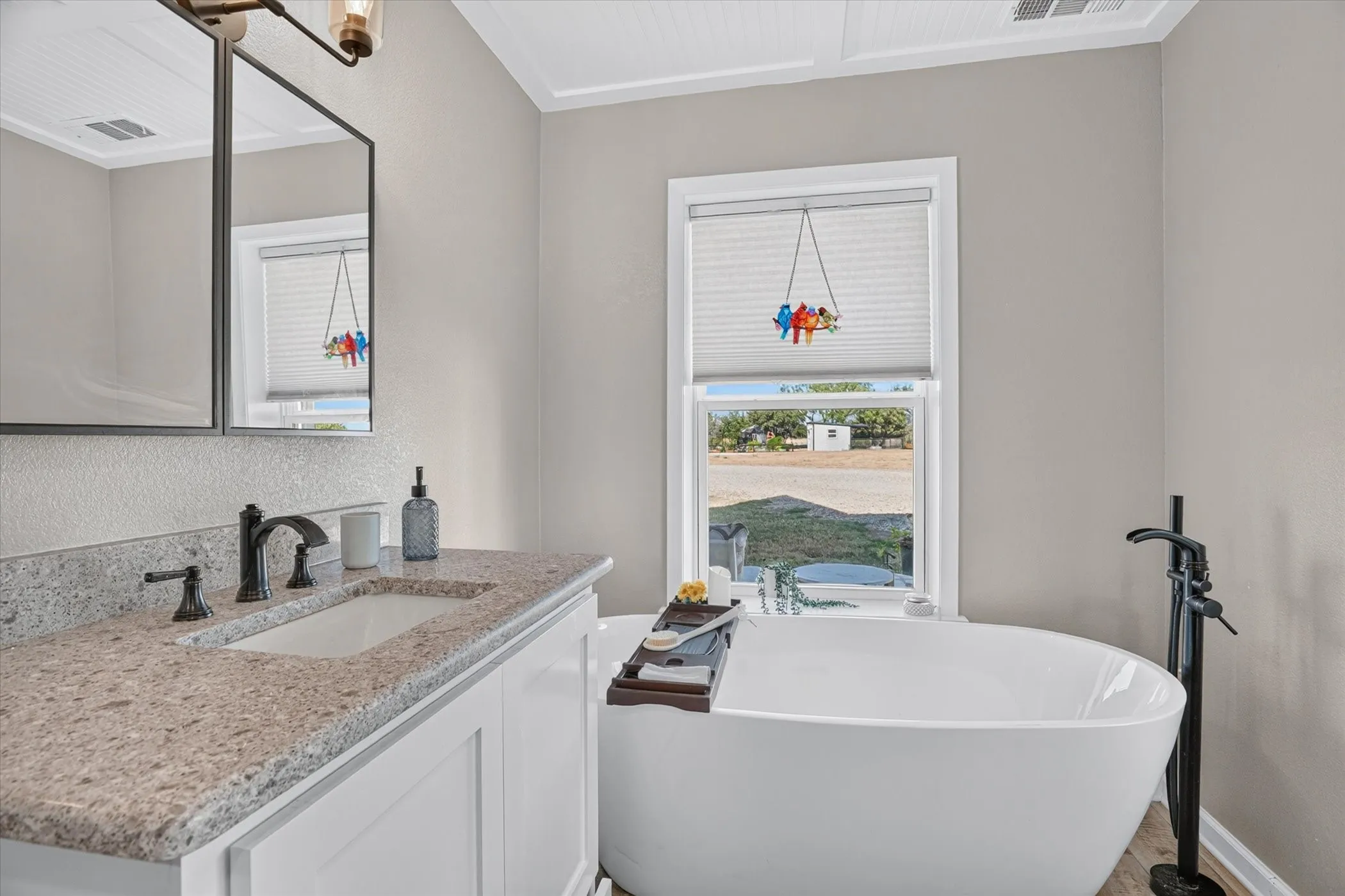 White freestanding soaking tub with a matte black floor-mounted faucet