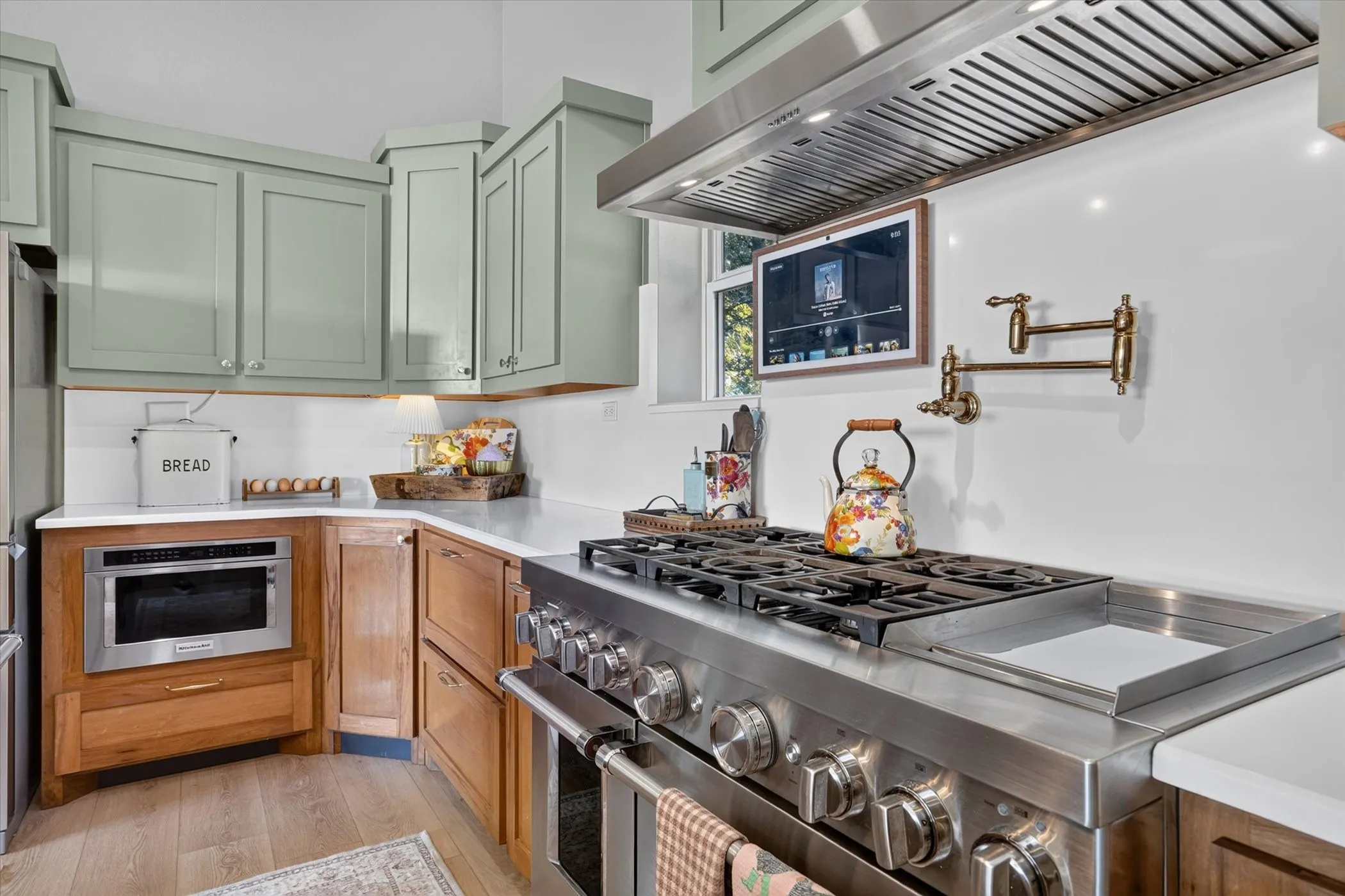 Stainless steel range with integrated griddle, coordinating range hood, and brass pot filler