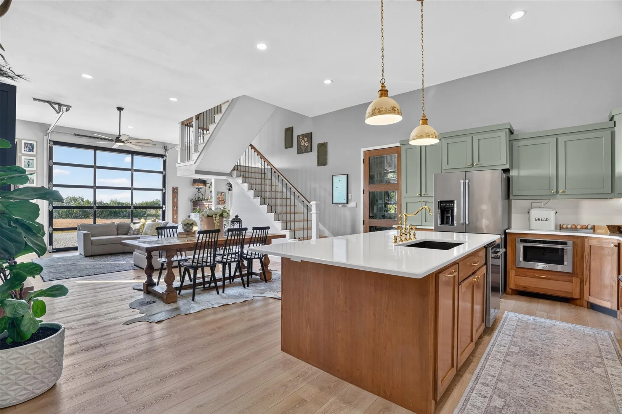 Open-concept living space featuring wood-finish flooring, a full-lite garage-style door, and a staircase with wood handrails