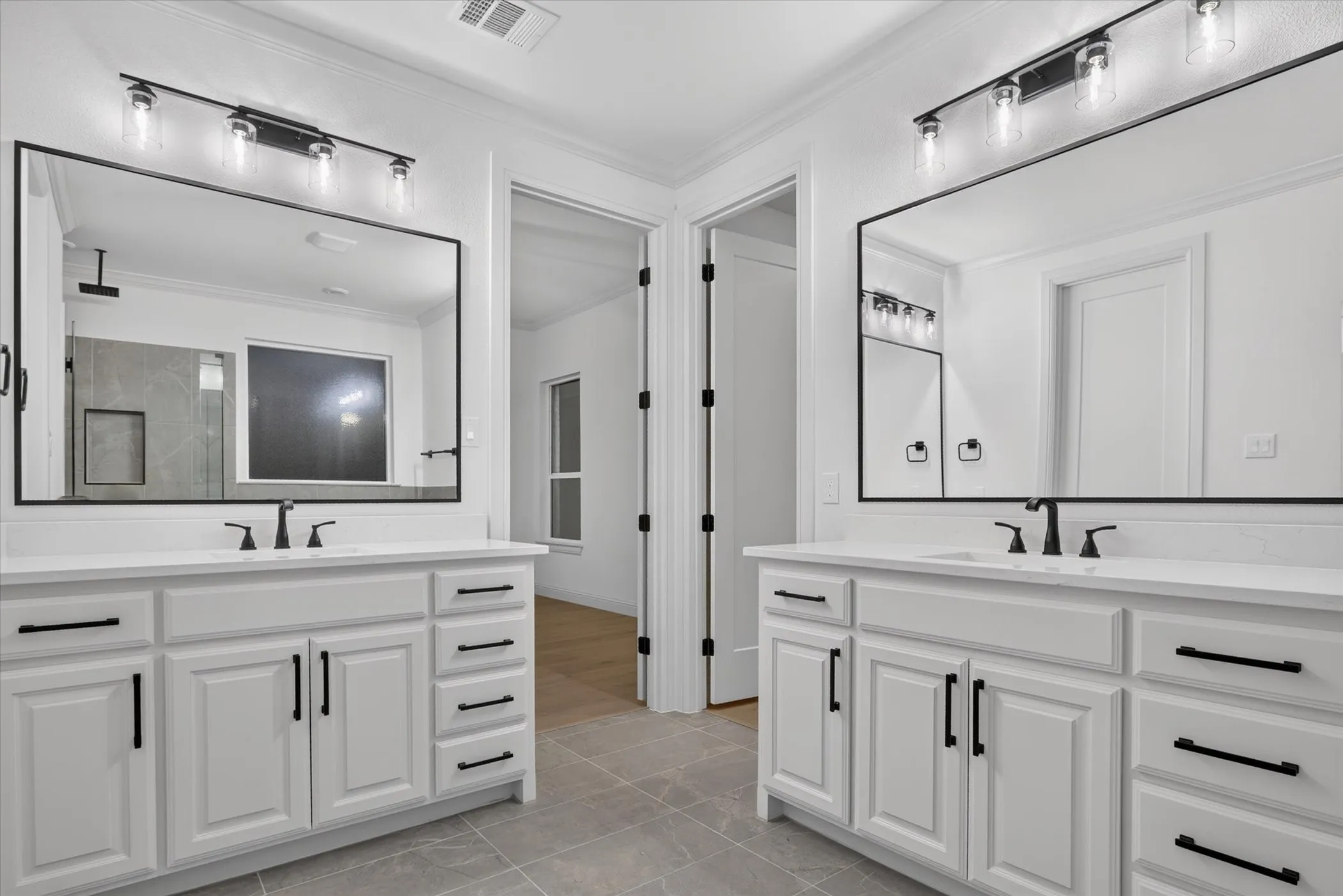 Dual white vanities with black hardware, white countertops, and undermount sinks