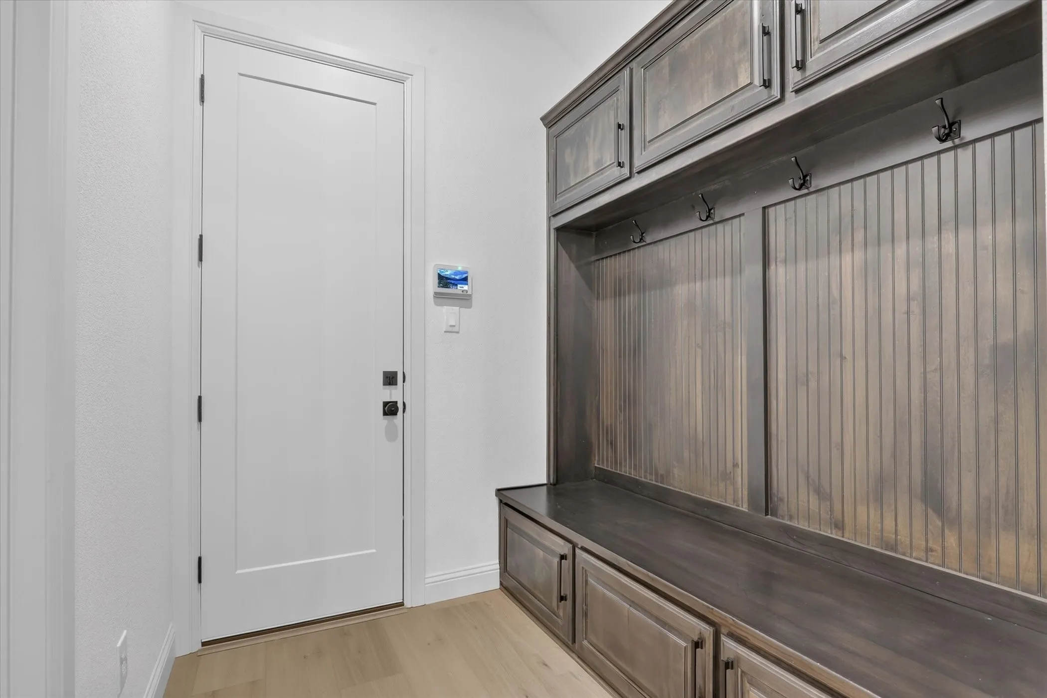 Built-in wood storage system featuring upper cabinetry, lower drawers, and a bench