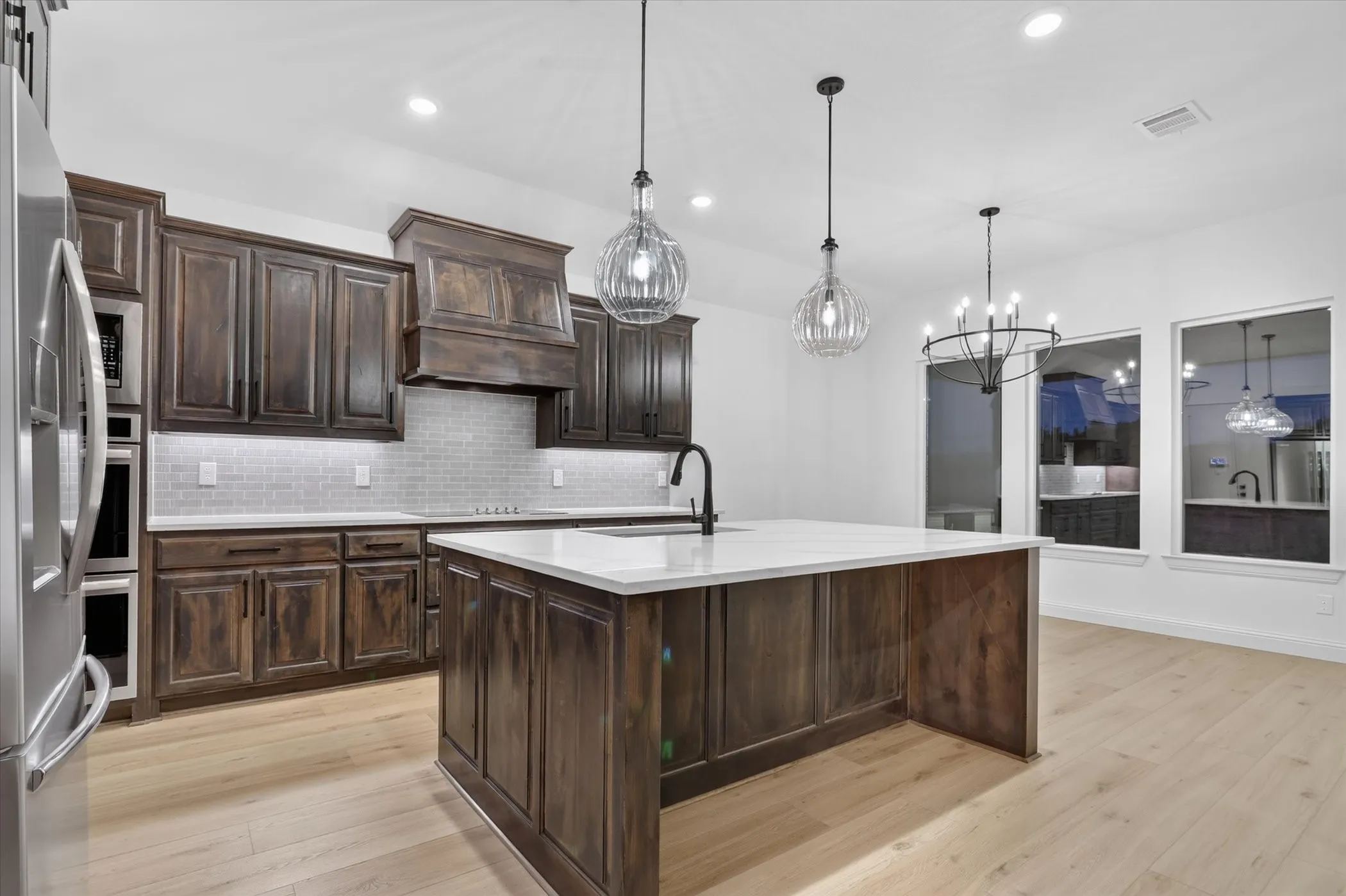 Kitchen featuring wood-finish cabinetry, light-toned wood-finish flooring, white countertops, and stainless steel appliances