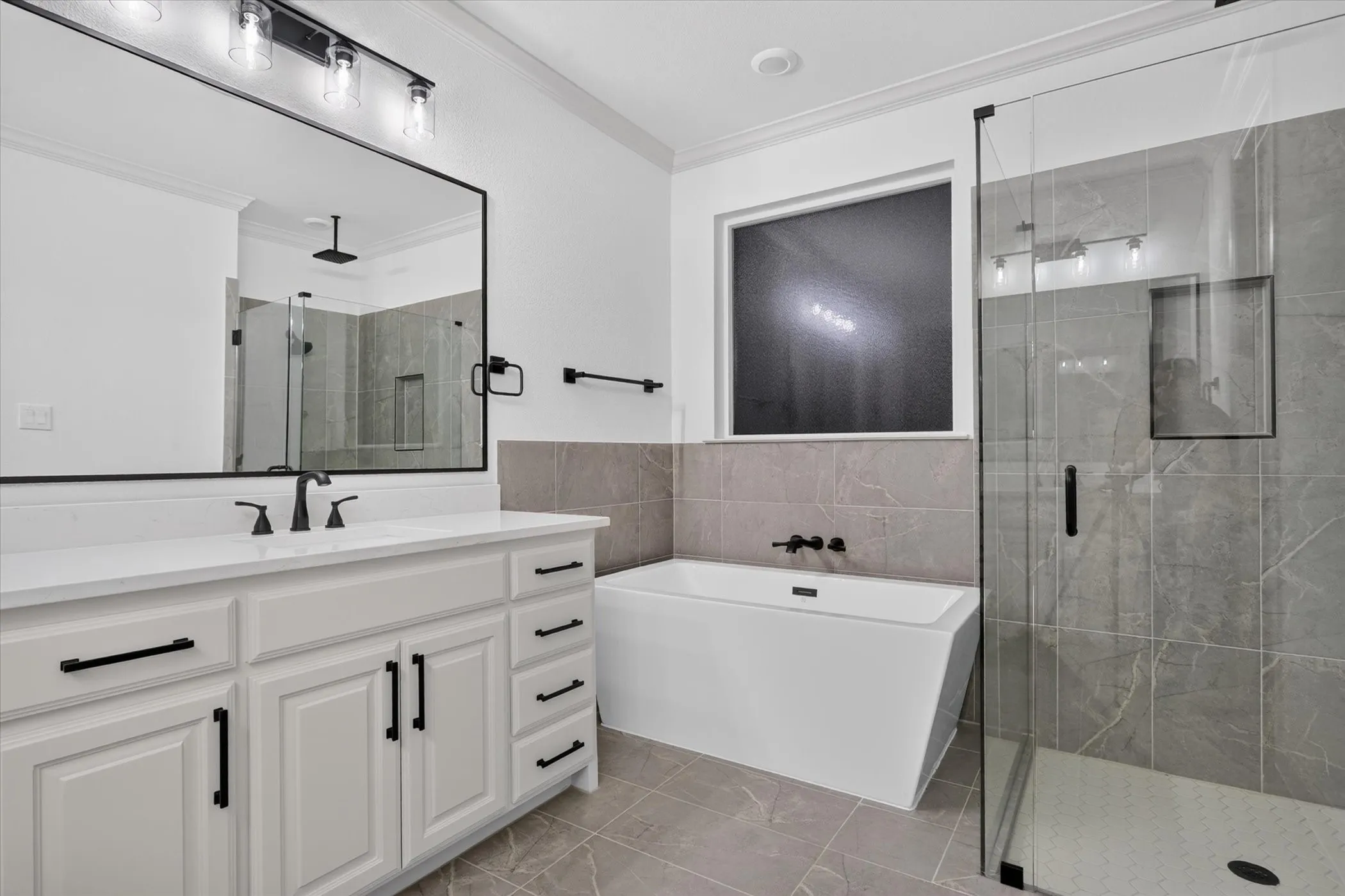 White vanity with multiple storage drawers and cabinet doors, matte black hardware, and a single basin