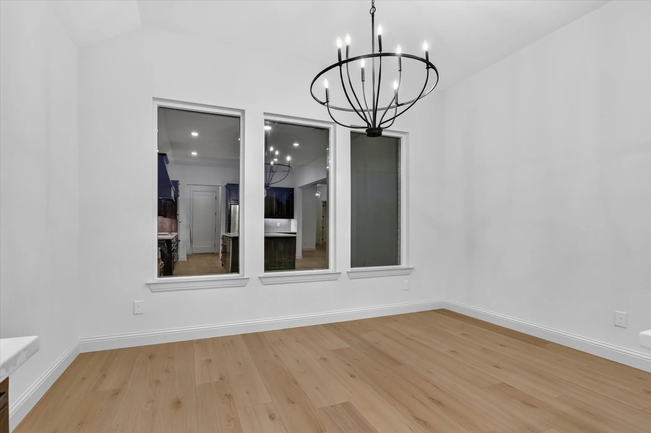 Vaulted ceiling with an orb chandelier, light wood-finish flooring, and white walls