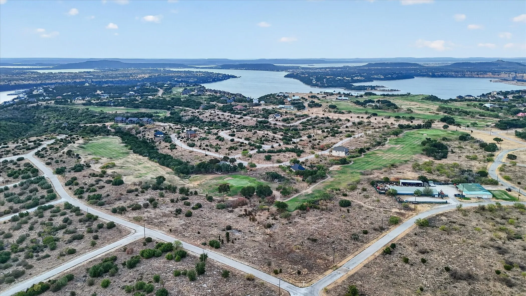 Expansive landscape with a prominent lake, winding roads, and scattered buildings