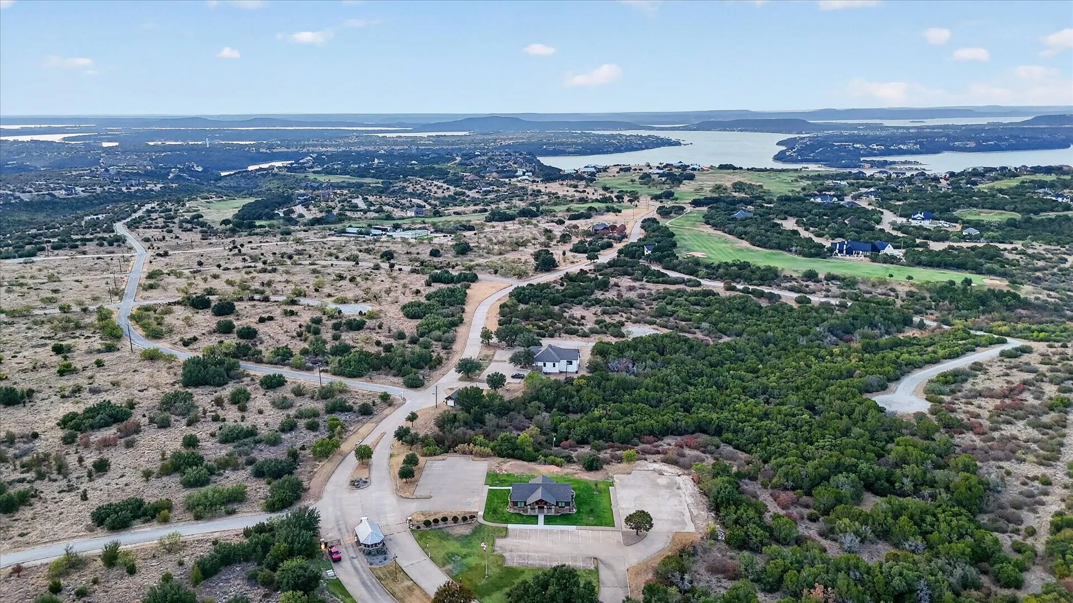 Expansive parcel featuring a large body of water, scattered trees, and paved roads
