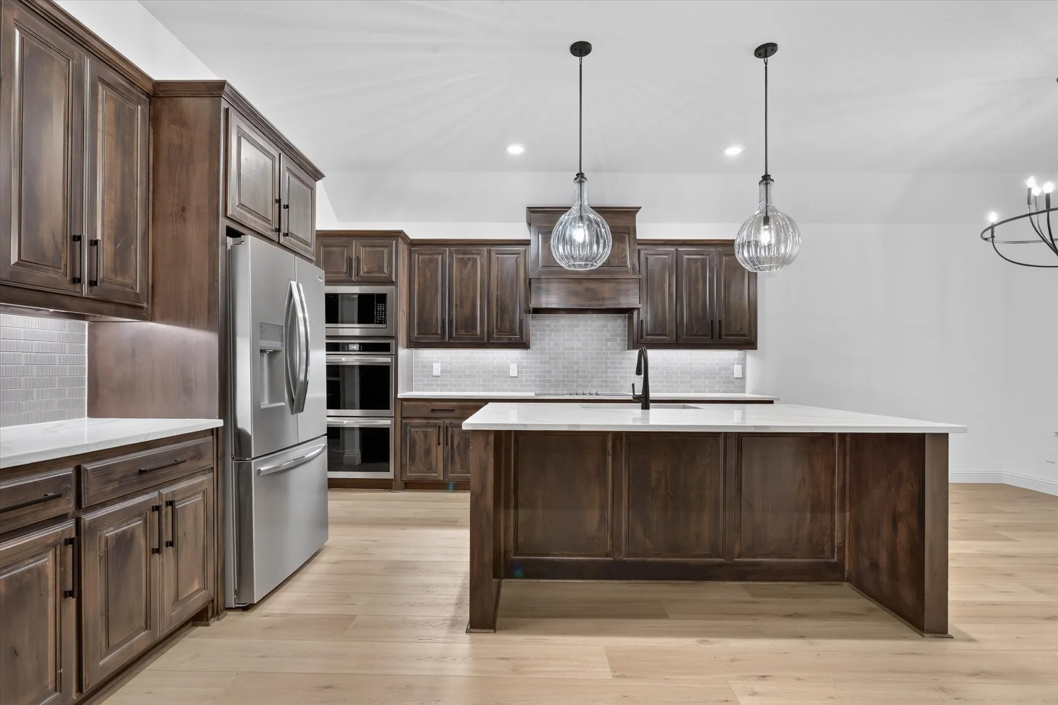 Kitchen featuring wood cabinetry, stainless steel appliances, a center island with a white countertop, recessed lighting, and wood-finish flooring