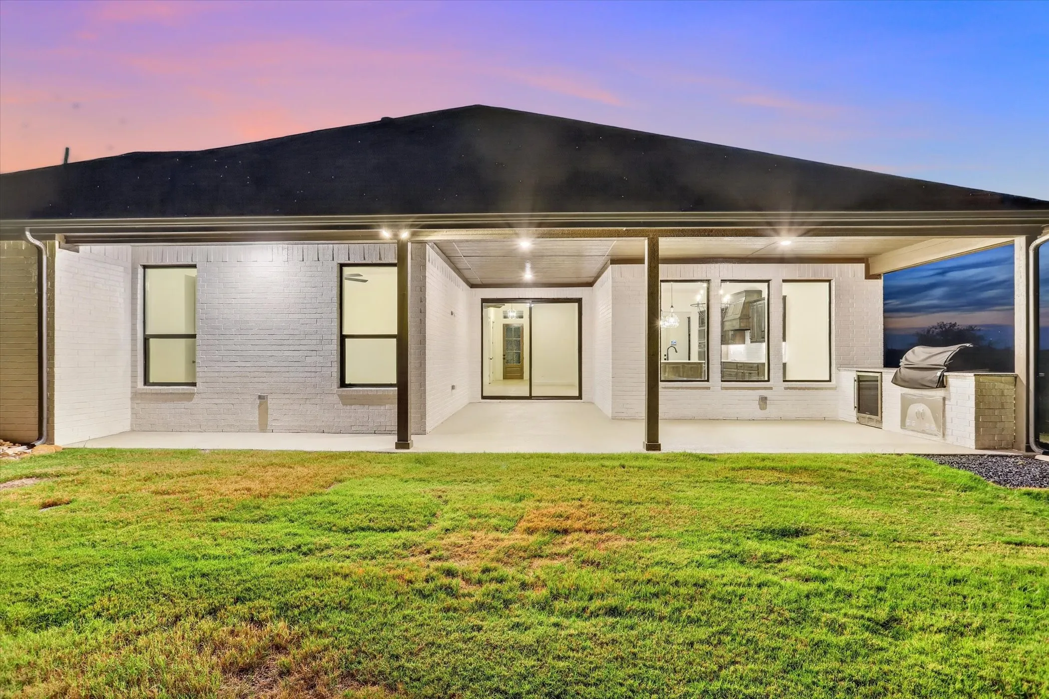 Covered patio featuring recessed lighting, an integrated outdoor grill, and white brick exterior