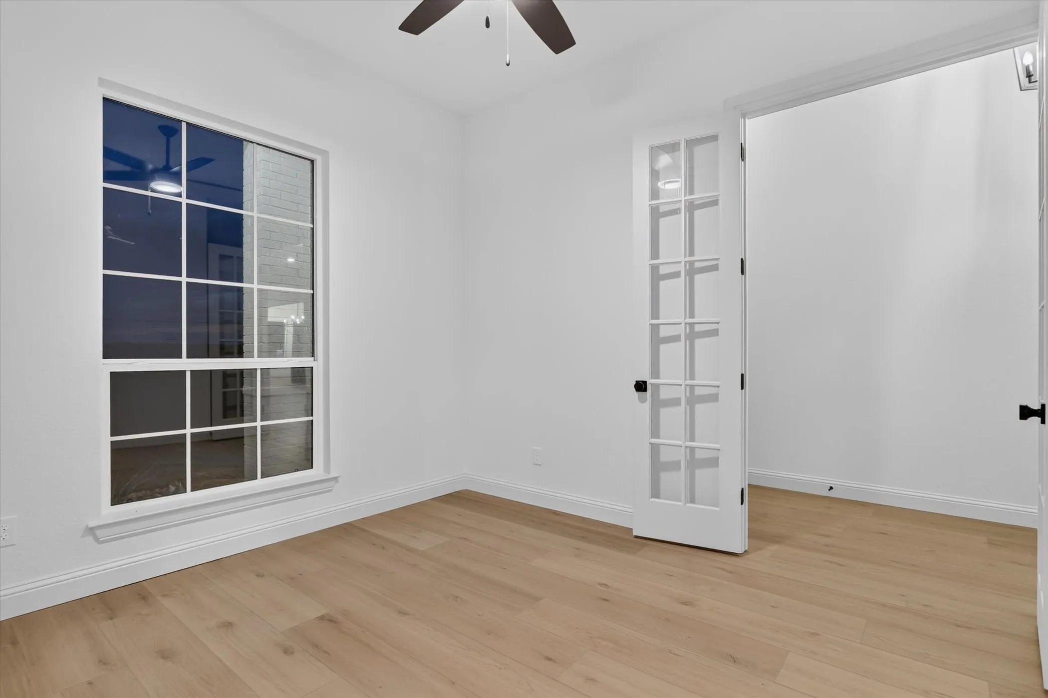 Wood-finish flooring, white walls, and a multi-pane window