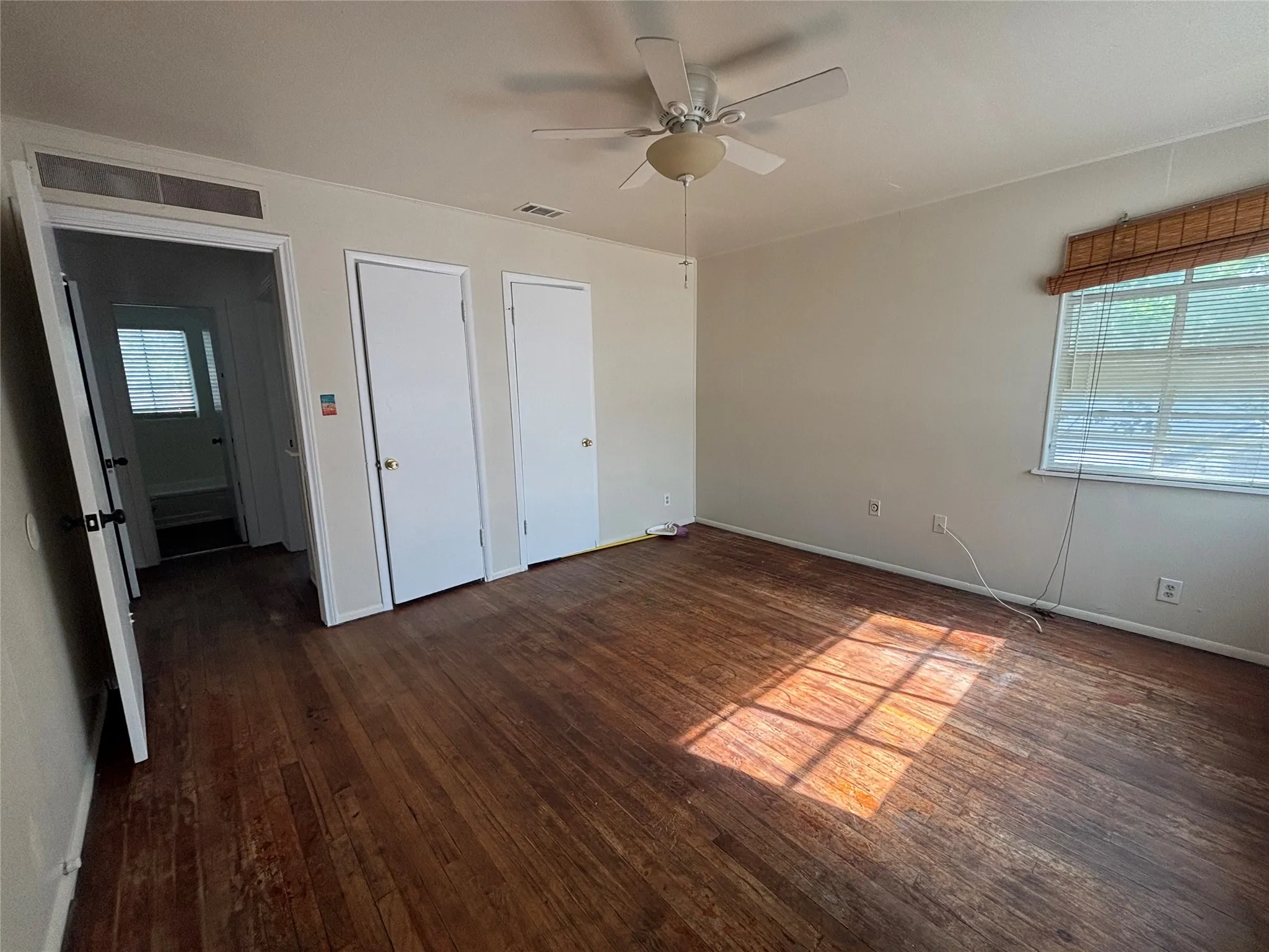 Hardwood-finish flooring, ceiling fan, and window with horizontal blinds