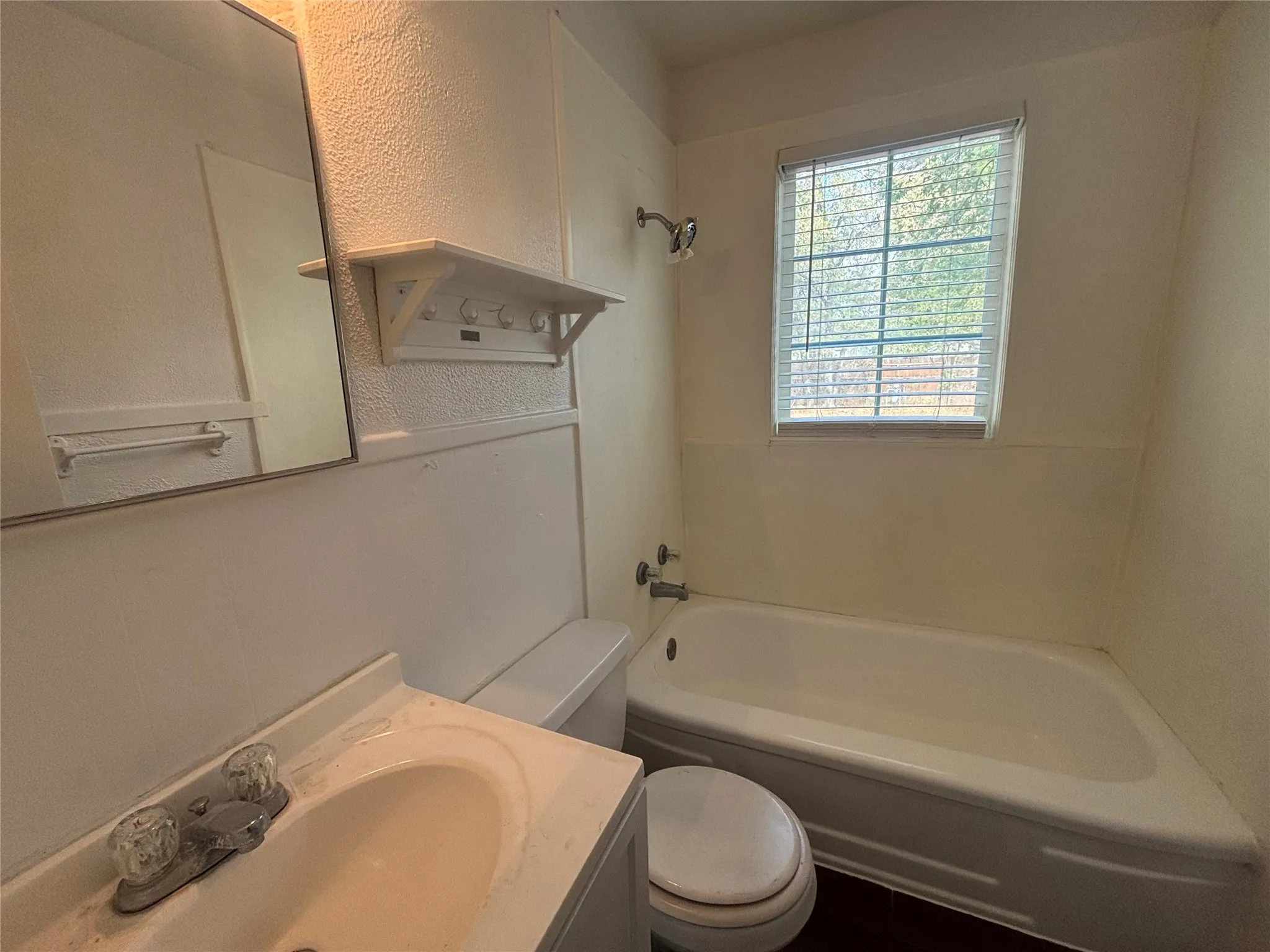 Bathroom with a vanity sink, toilet, bathtub, and window with blinds