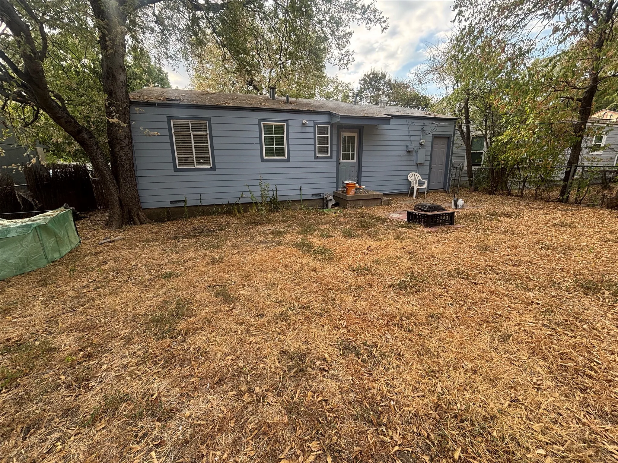 Expansive backyard with a fire pit, mature trees, and a utility shed
