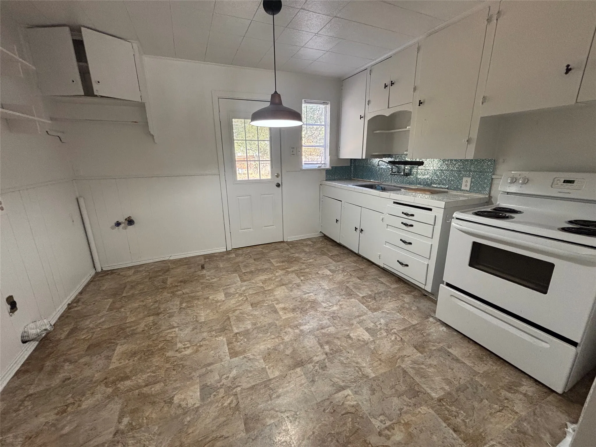 White cabinetry with dark hardware, a white electric range, and a tiled backsplash