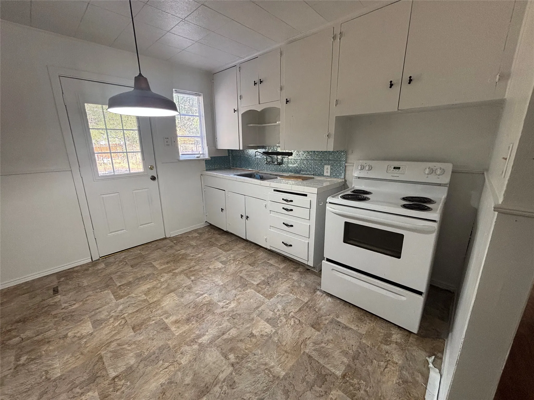 Kitchen featuring white cabinetry, a white electric range, a white door with window panes, and patterned tile flooring