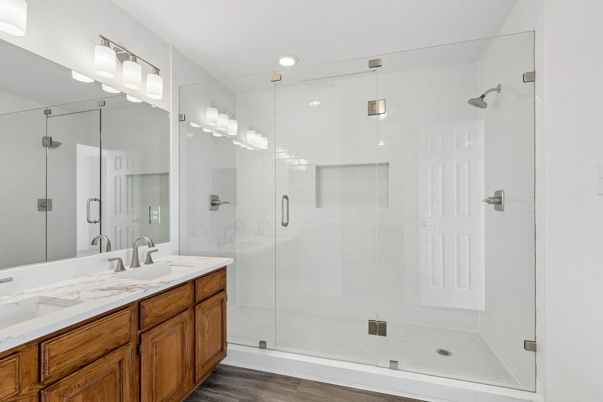Custom oversized walk in shower in primary bath gives you two shower heads and shampoo niche