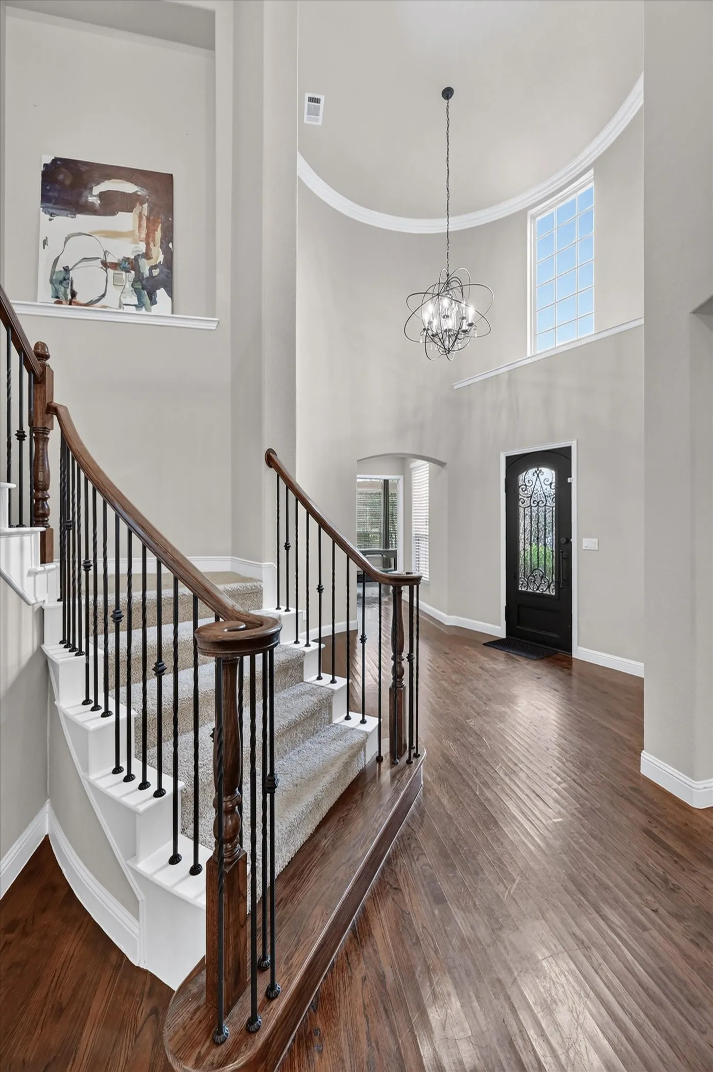Grand two-story foyer with soaring curved ceiling, abundant natural light from upper windows, and a striking pendant fixture