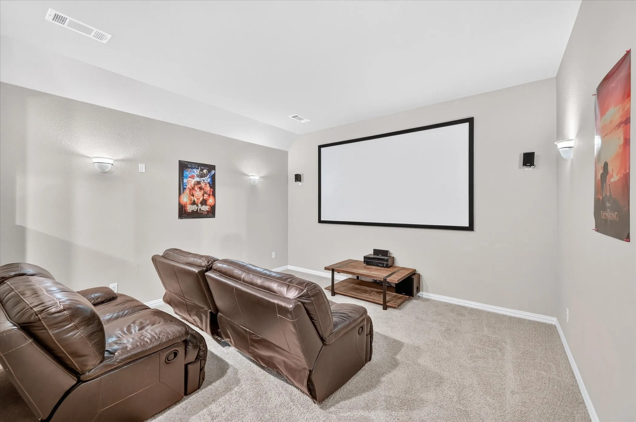 Dedicated media room featuring a large projection screen, wall-mounted speakers, and recessed ceiling lighting