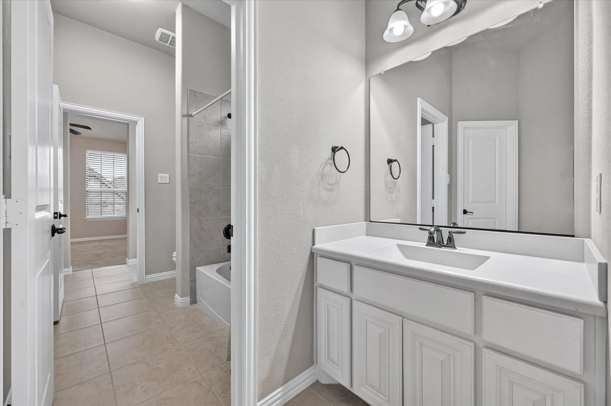 Vanity with integrated sink, white cabinetry, and wall-mounted lighting