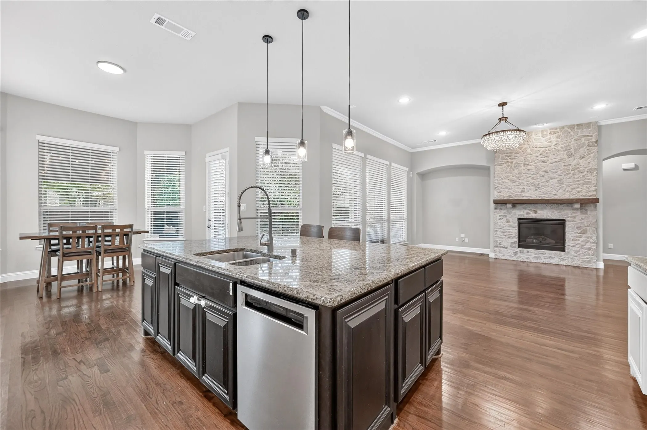 Kitchen island with granite countertop, stainless steel sink, and pendant lighting