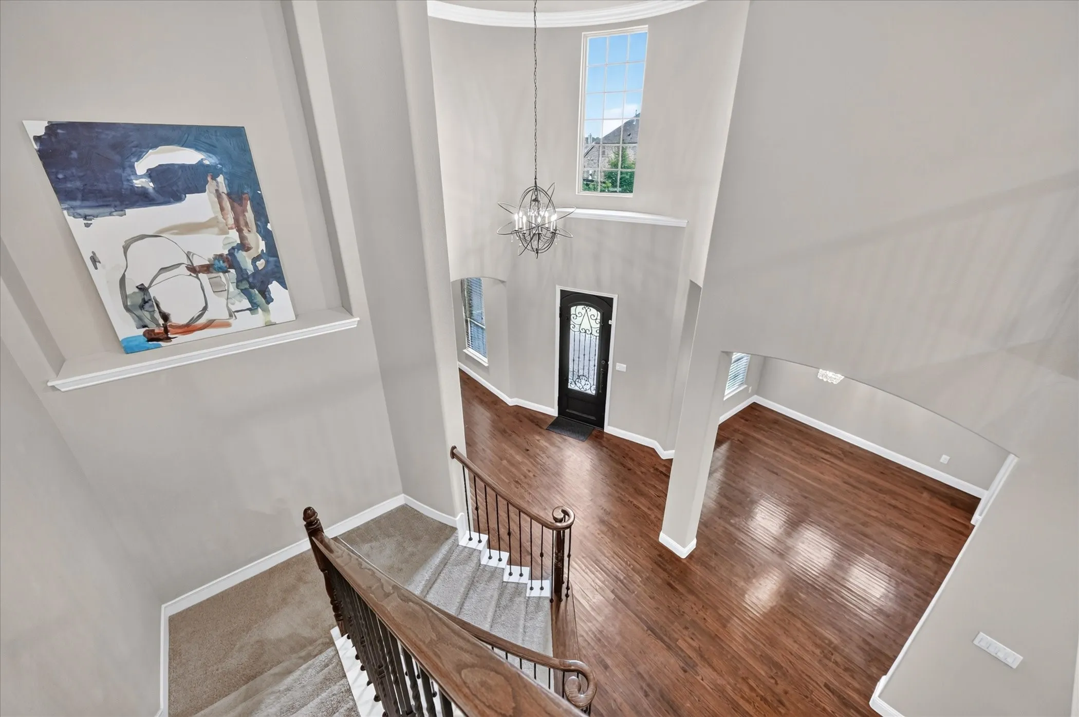 Two-story foyer with a decorative chandelier, curved staircase with wood-finish railing, and wood-finish flooring