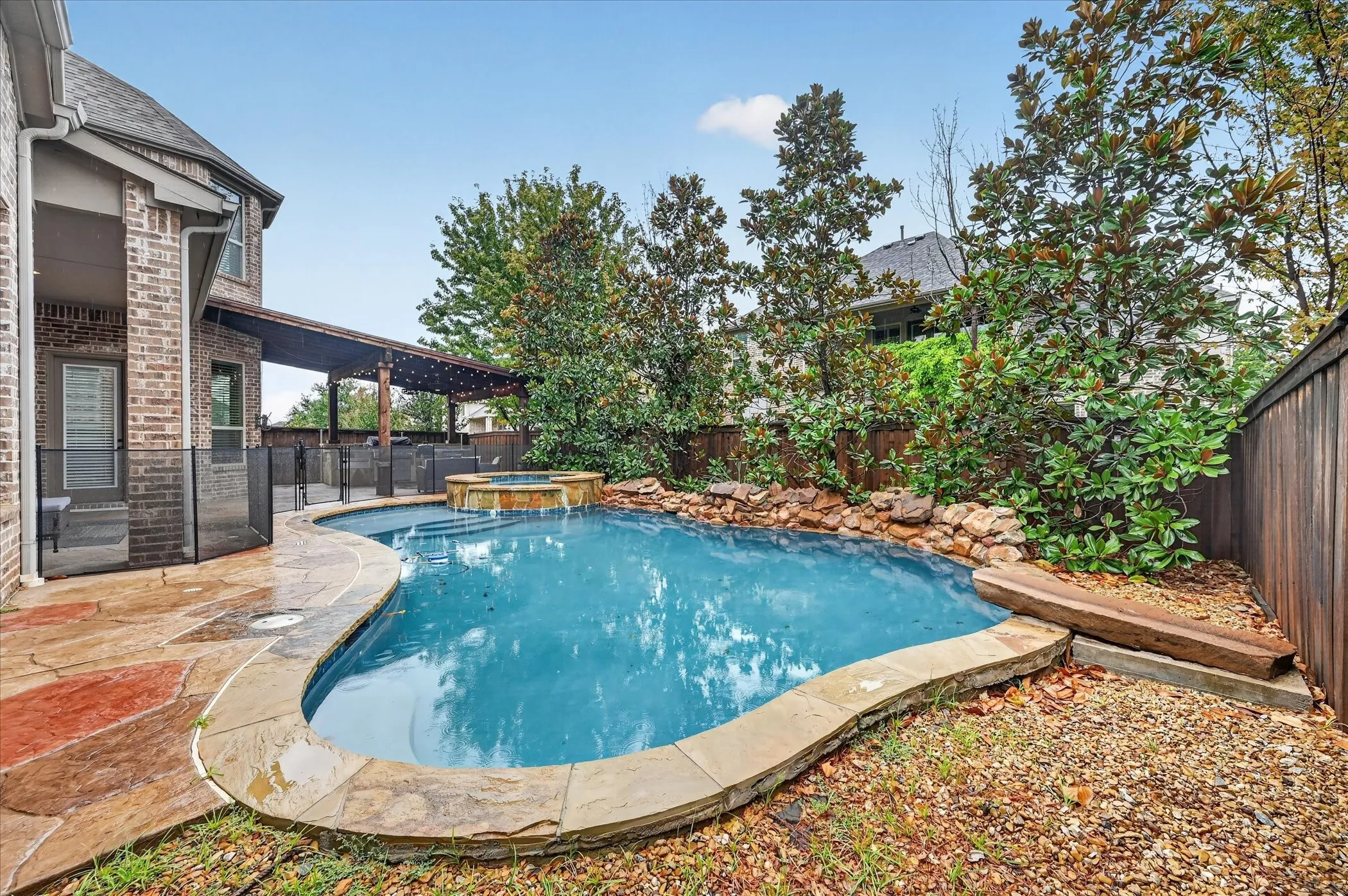 Curved swimming pool with an integrated spa, surrounded by natural stone coping and flagstone patio