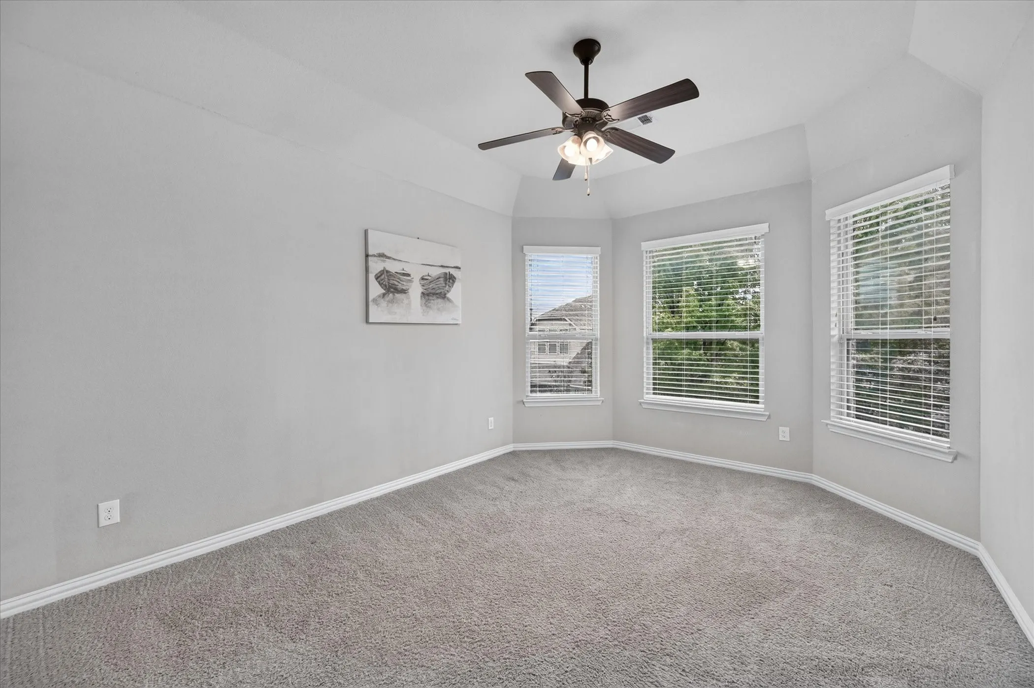Tray ceiling with recessed lighting and a ceiling fan, three windows with blinds, and light gray wall paint