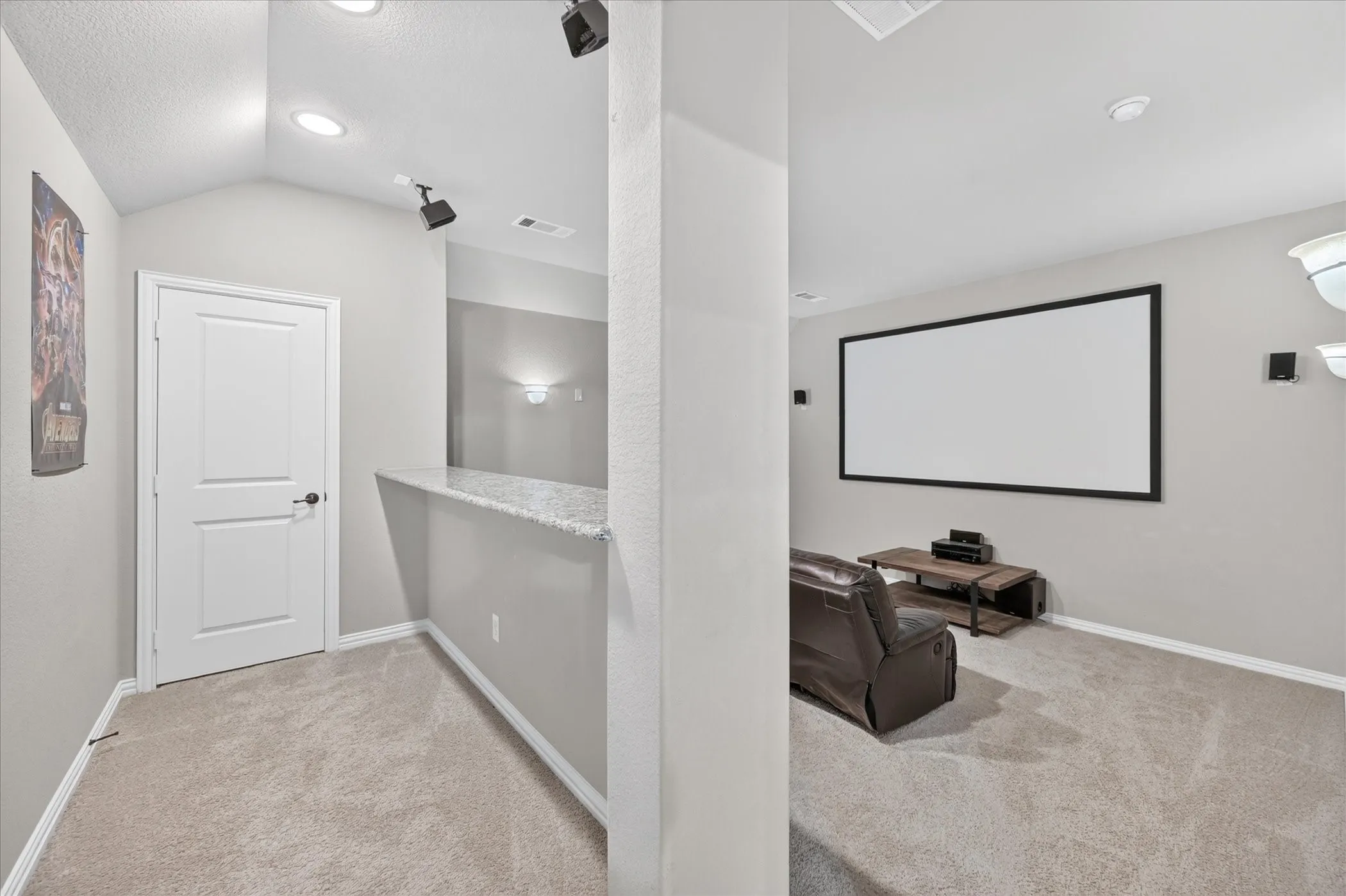Dedicated media room featuring a large projector screen, recessed lighting, wall-mounted sconces, and carpeting