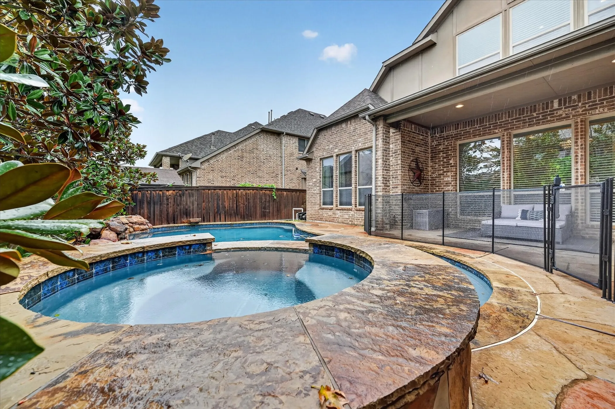 Swimming pool with integrated spa, stone coping, and blue tile accents