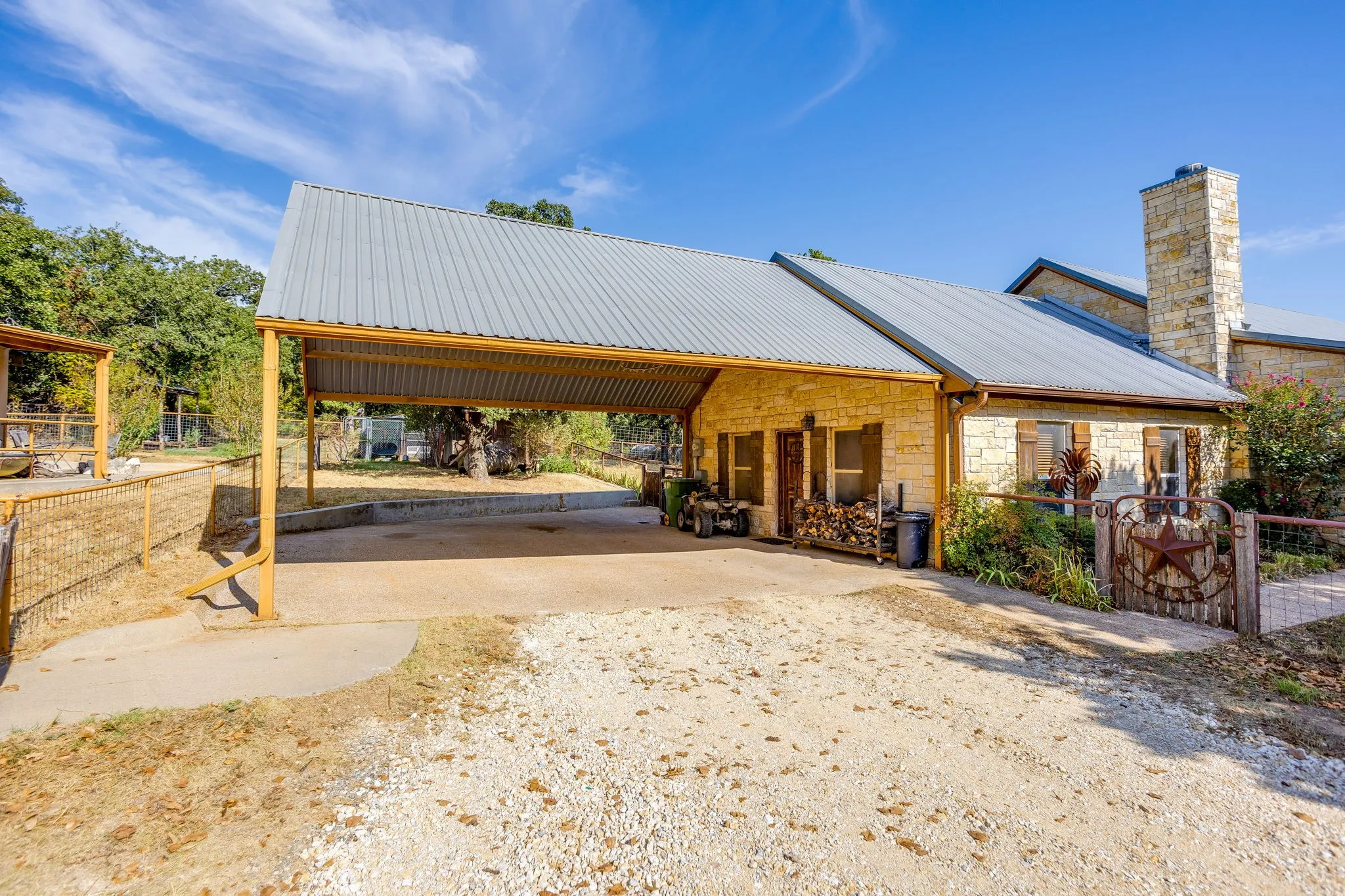Stone exterior featuring a metal roof, an attached carport, a stone chimney, and decorative window shutters