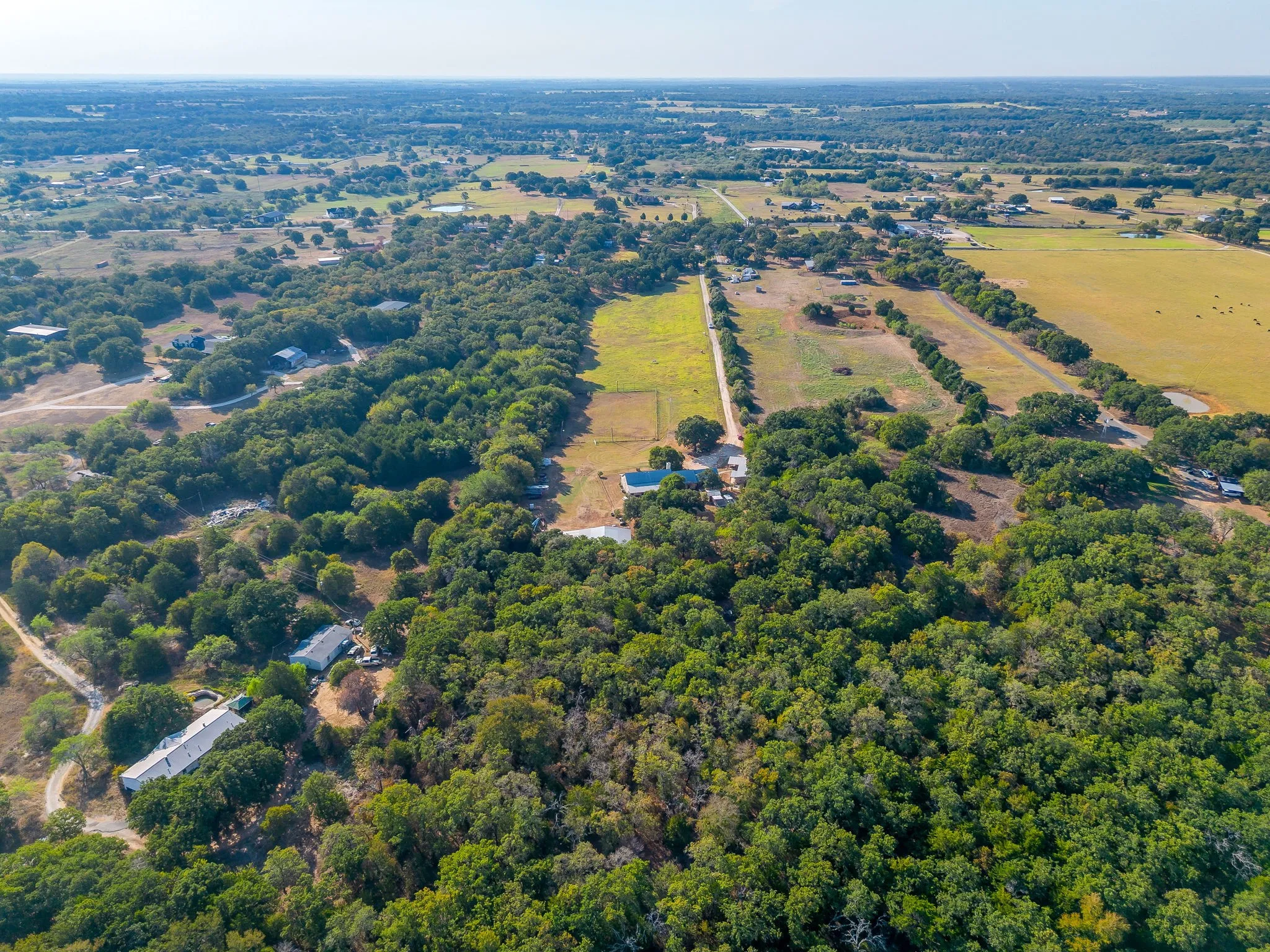Expansive wooded acreage with a mix of dense tree cover and open fields, showcasing multiple structures