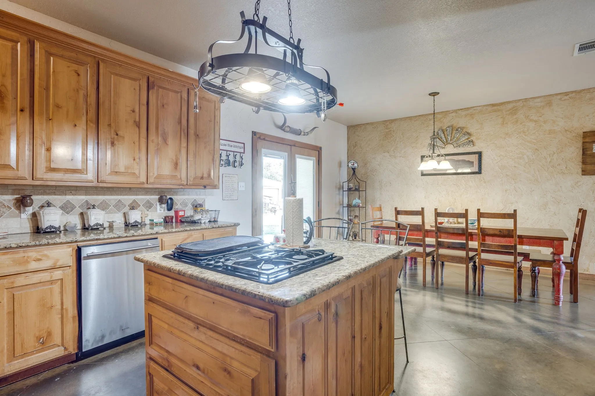 Kitchen featuring wood cabinetry, granite countertops, tile backsplash, and stainless steel dishwasher