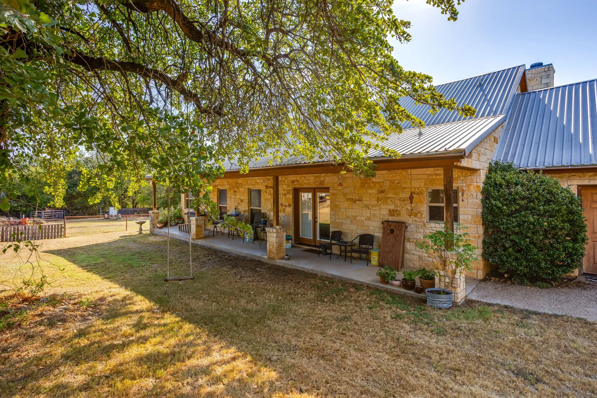 Stone exterior with a covered patio, metal roof, and double glass doors