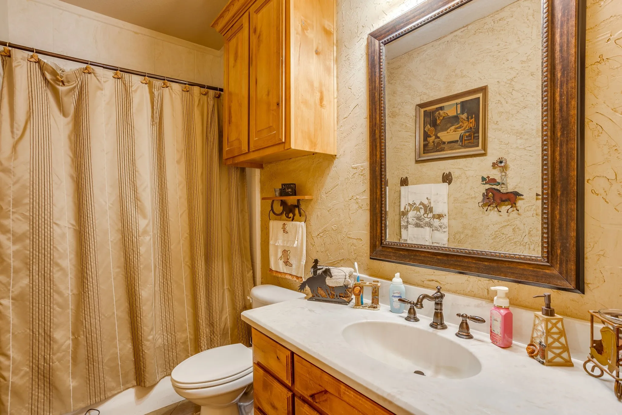 Bathroom with a single vanity, undermount sink, bronze-finish faucet, framed mirror, and wood cabinetry