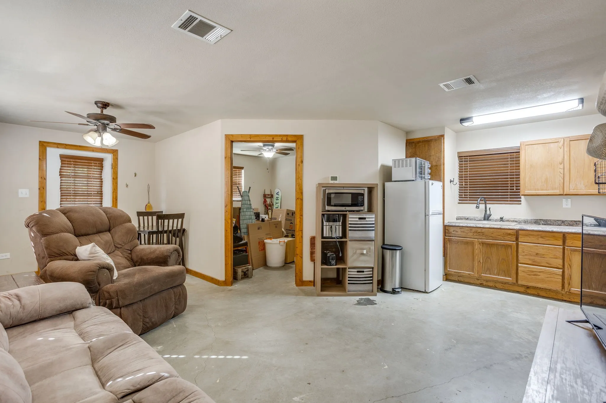 Concrete-finish flooring with wood-trim windows, a ceiling fan, and built-in cabinetry with a sink