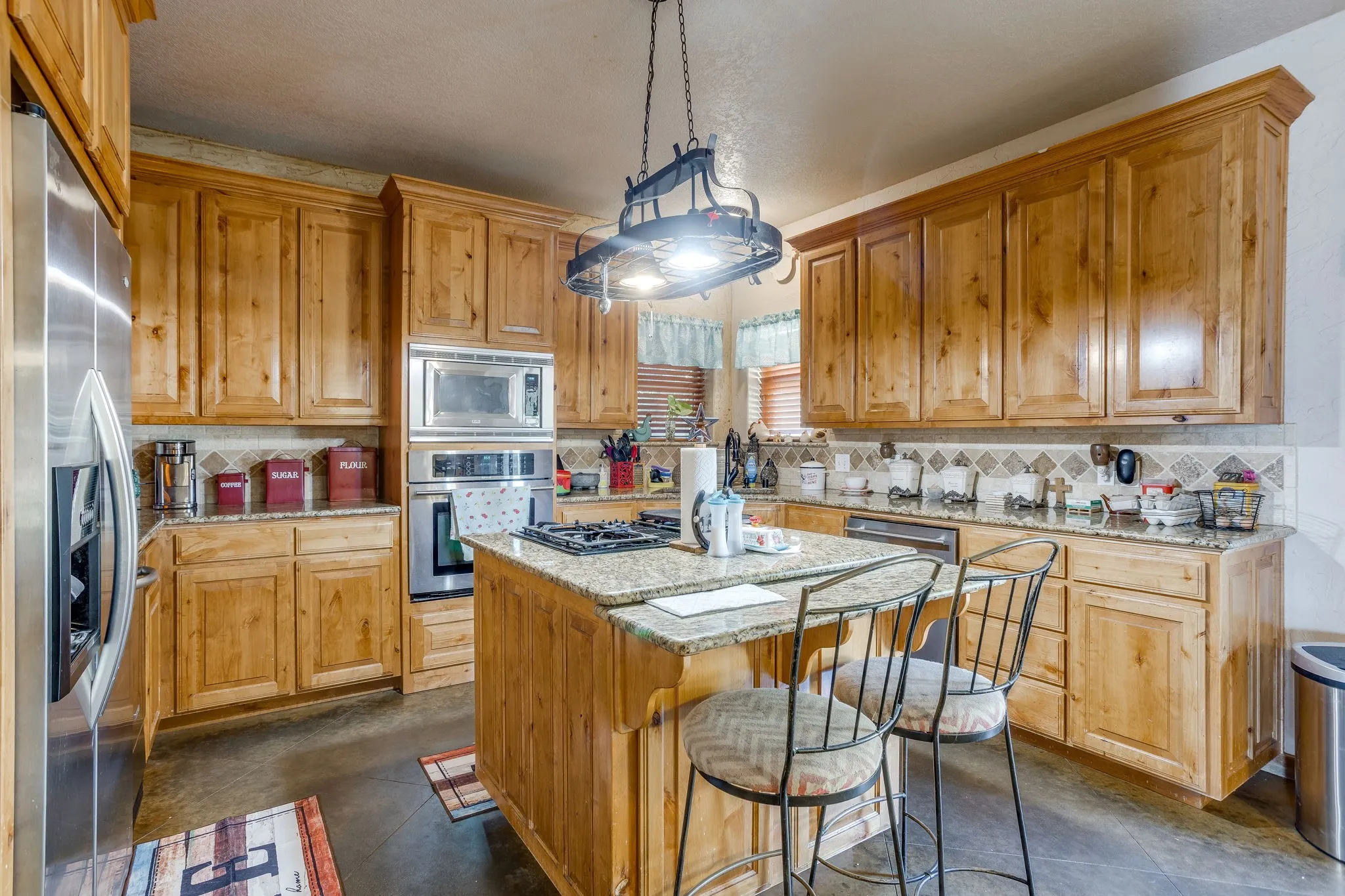 Kitchen featuring wood cabinetry, stainless steel appliances, a center island with seating, and granite countertops