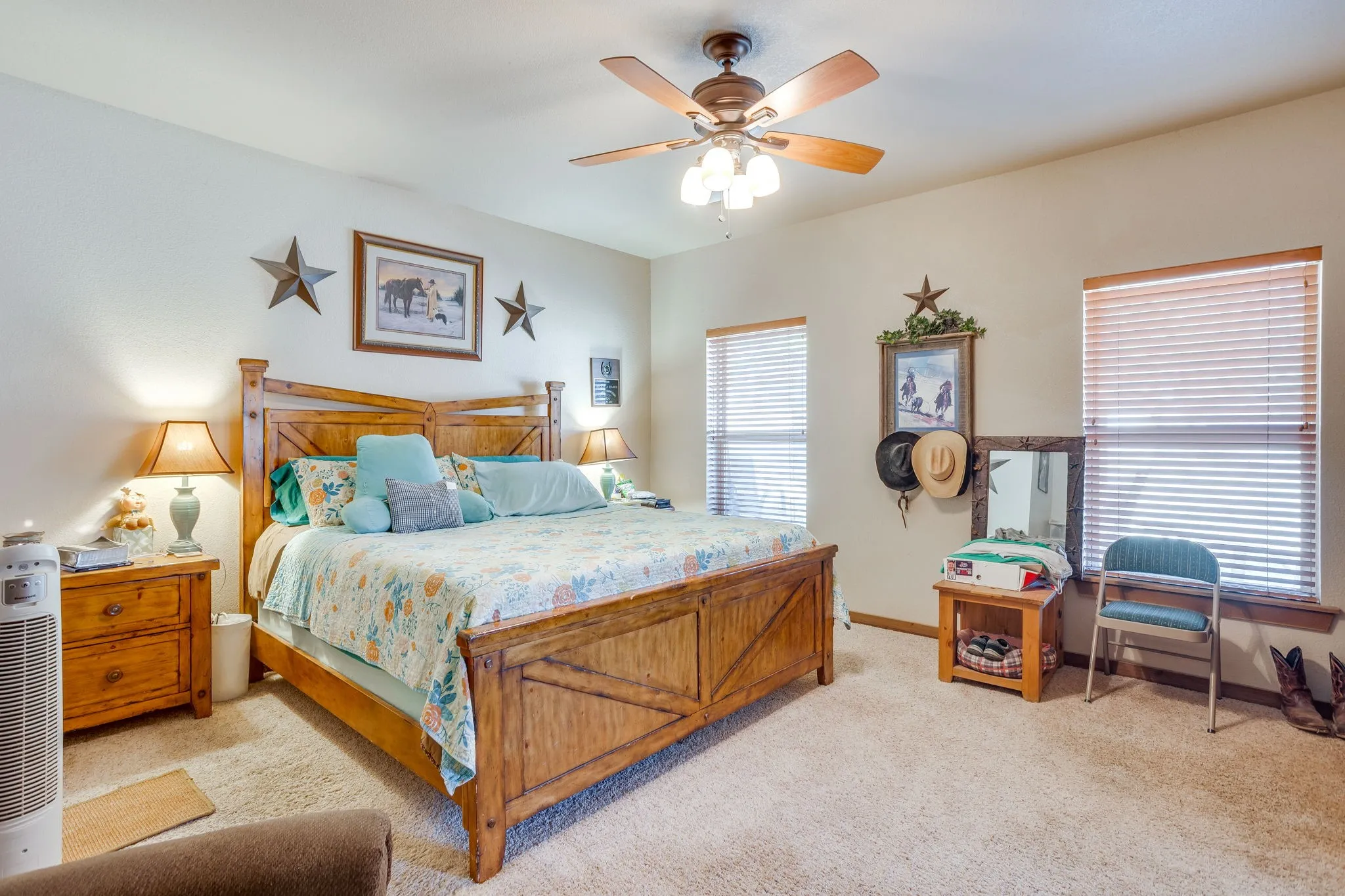 Carpeted bedroom featuring a ceiling fan with integrated lighting, two windows with blinds, and neutral wall tones