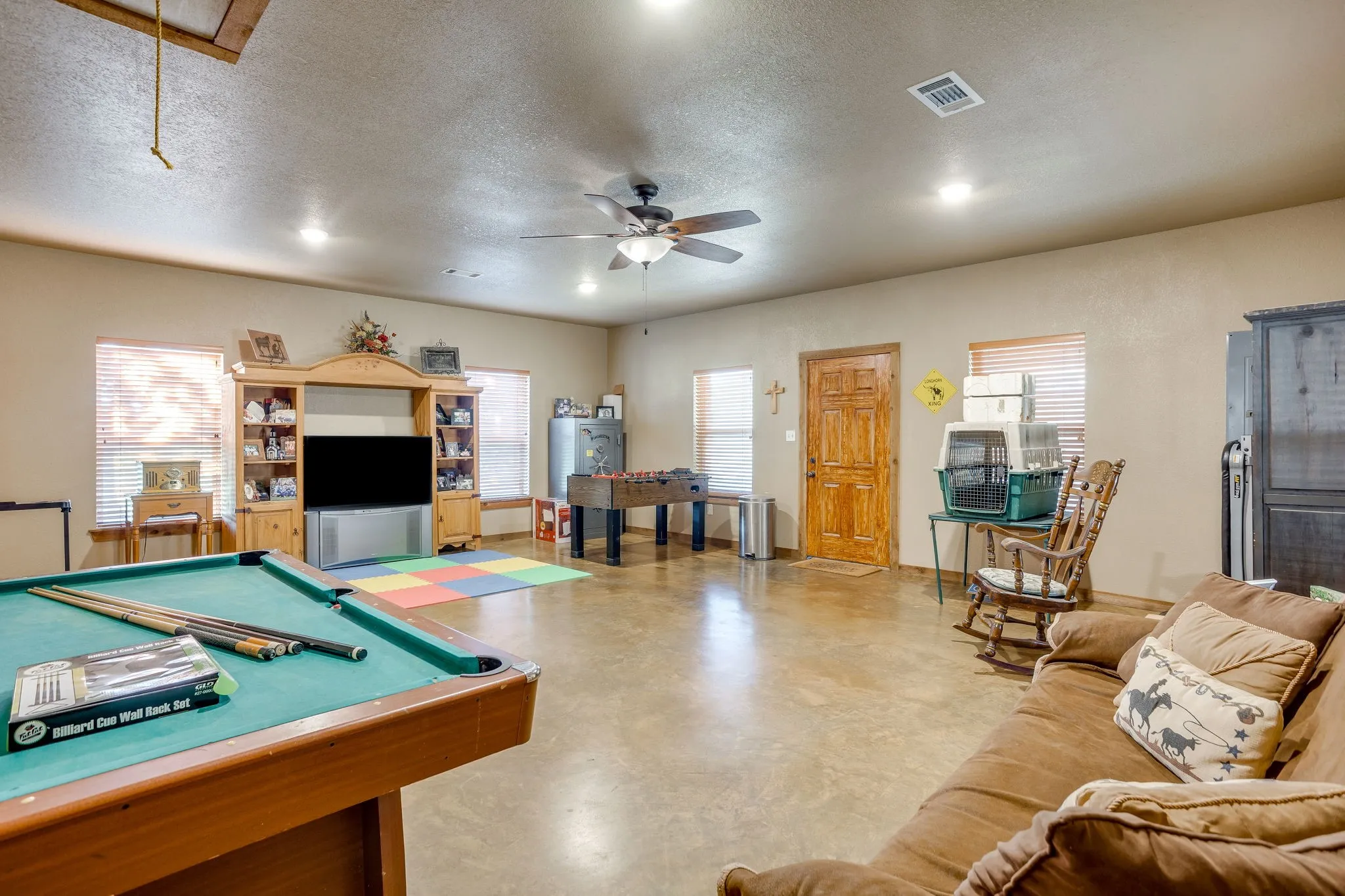Spacious room featuring concrete flooring, a ceiling fan, recessed lighting, and multiple windows with blinds