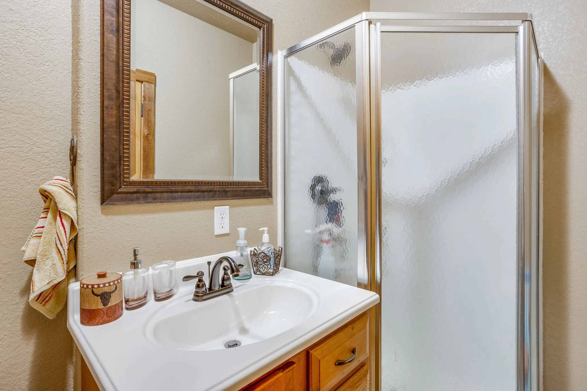 Wood-finish vanity with white countertop, integrated sink, and bronze-finish faucet