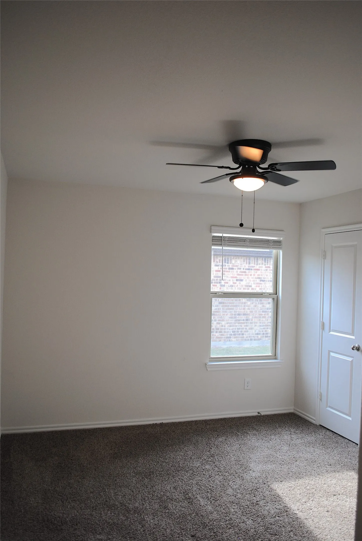 Recessed window with blinds, overhead ceiling fan with lighting, light-toned walls, and neutral carpet flooring