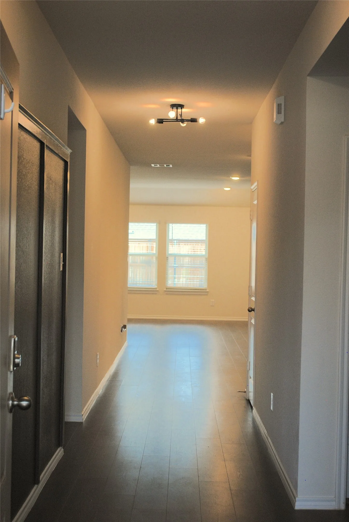 Hallway featuring dark wood-finish flooring, recessed lighting, a modern ceiling light fixture, and neutral wall tones