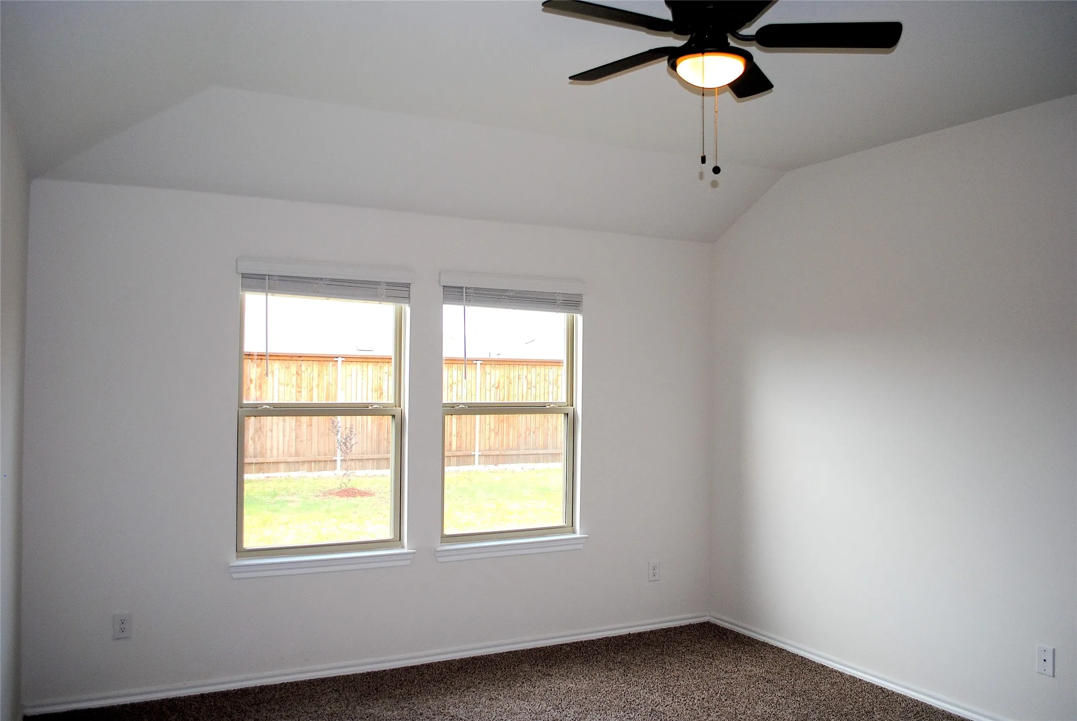 Ceiling fan with integrated lighting, dual windows with blinds, and neutral wall color