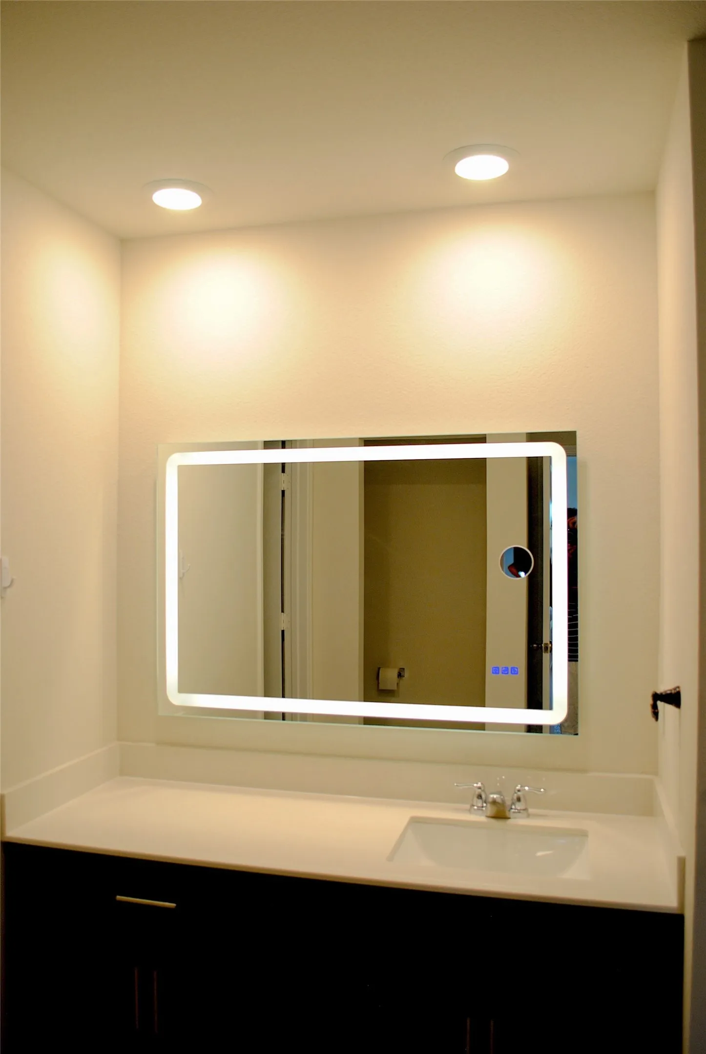 Modern bathroom vanity featuring an illuminated mirror with integrated LED lighting, white quartz countertop, and matte black hardware