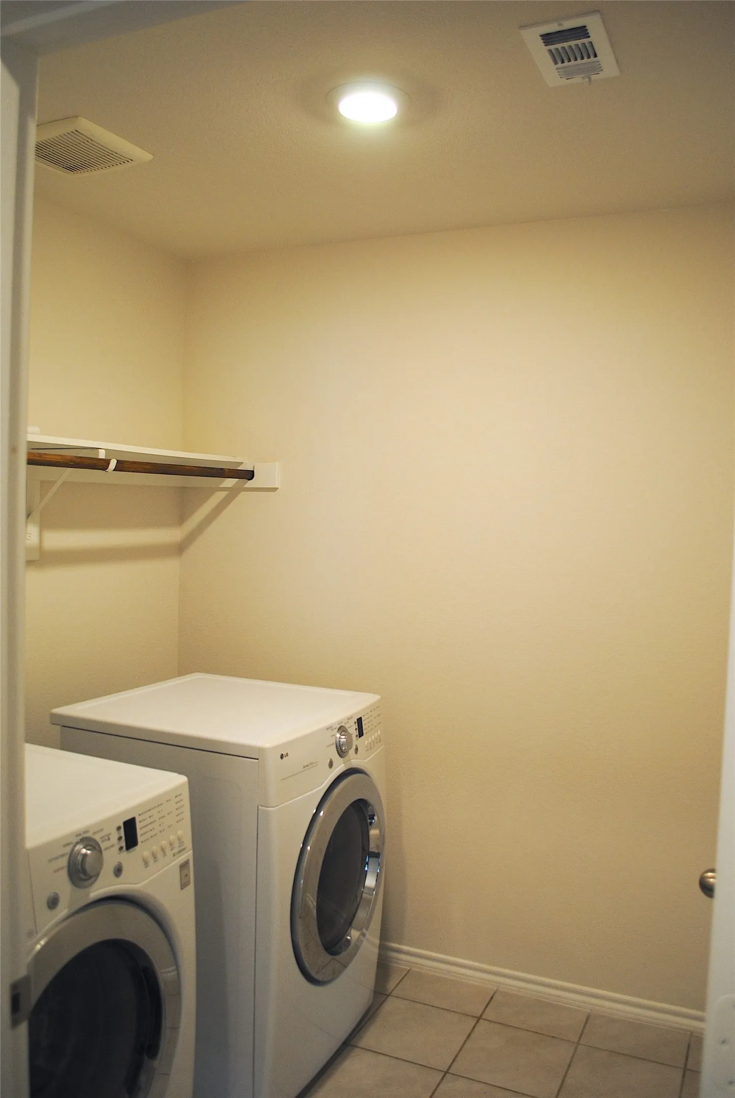 Laundry area featuring tile flooring, a wall-mounted shelf, and recessed lighting