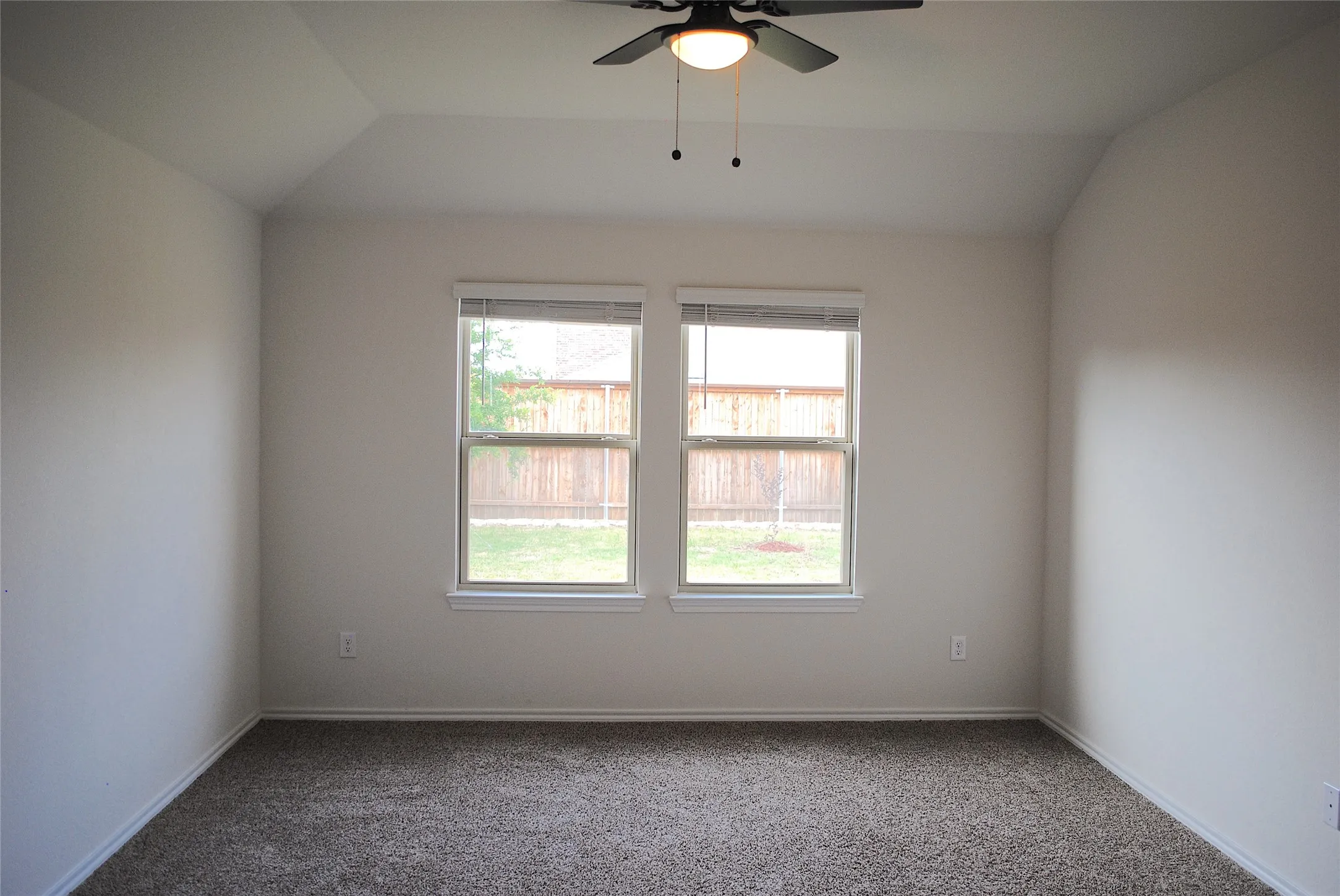 Tray ceiling with a ceiling fan, dual windows, and wall-to-wall carpeting