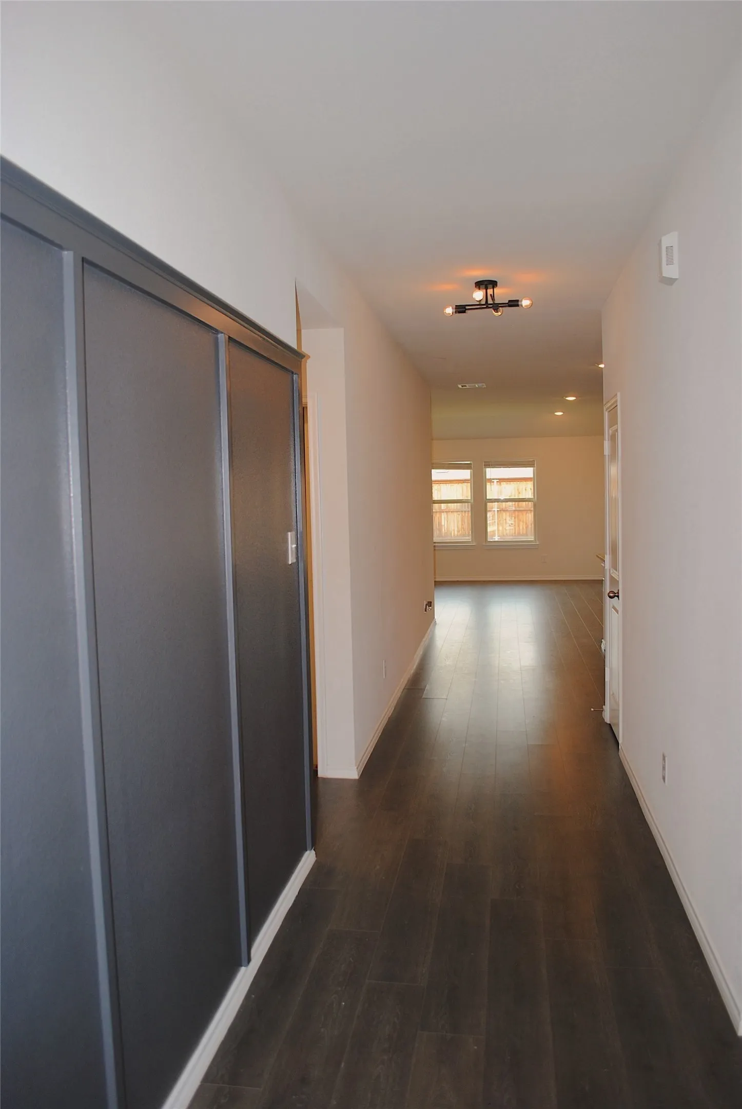 Wood-finish flooring throughout, modern semi-flush mount lighting fixture, recessed ceiling lighting, and panel detailing on wall