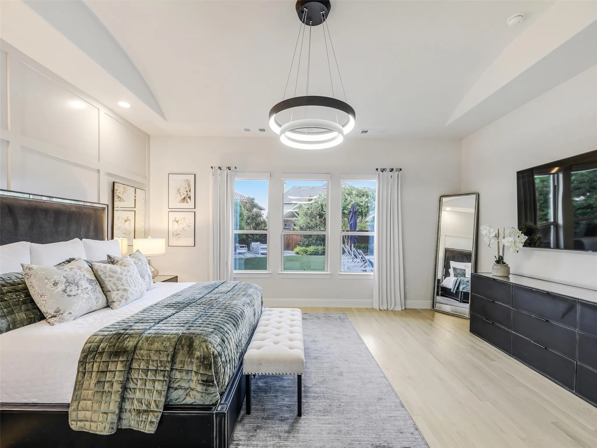 The downstairs primary retreat offers a private escape with a vaulted ceiling, chandelier, electric, remote-controlled shades, and a spacious ensuite bath