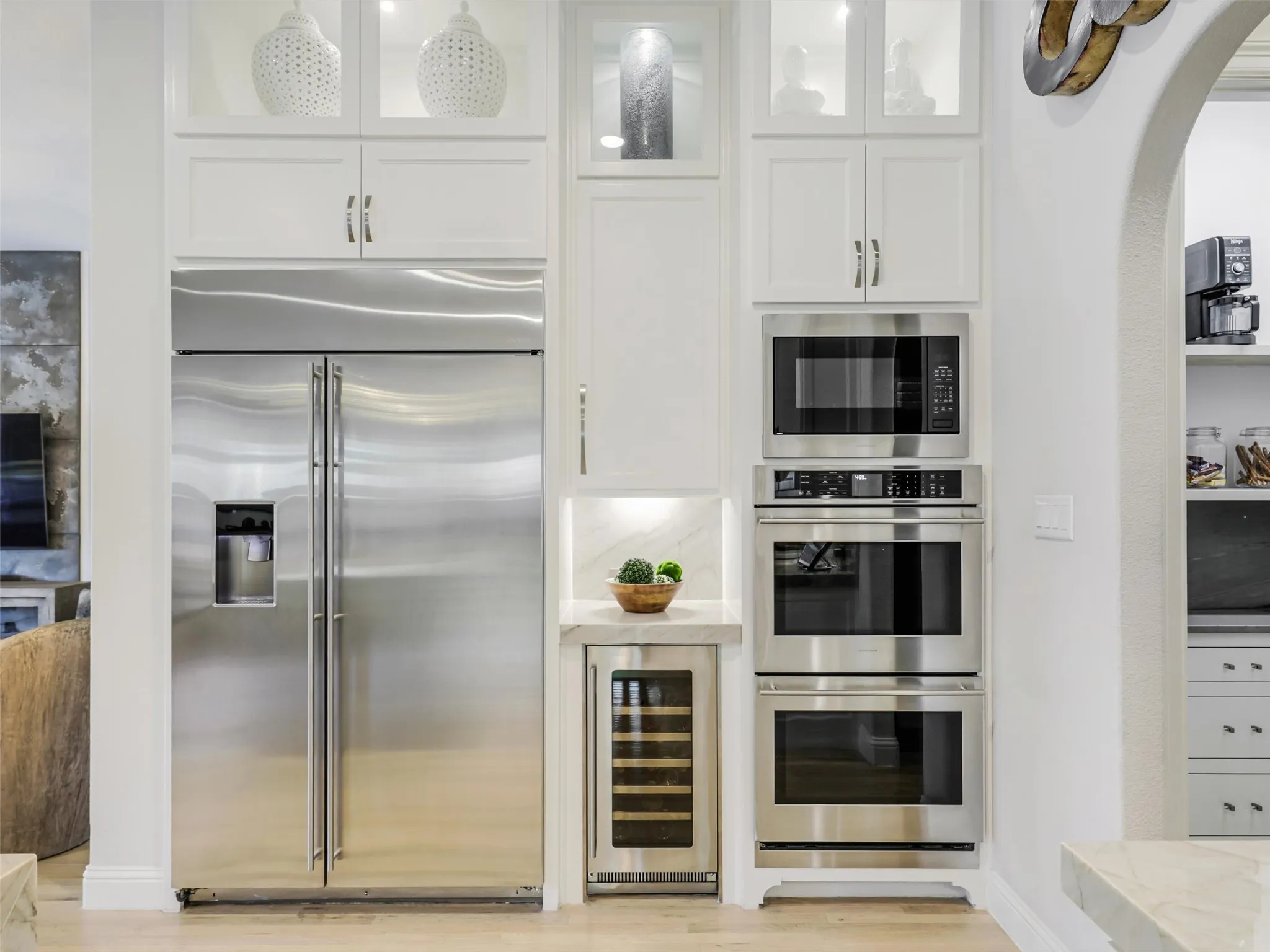 . Custom cabinetry provides abundant storage, while the oversized center island with breakfast bar offers additional prep and gathering space. Highend appliances include a built-in refrigerator, wine chiller, commercial-grade gas cooktop with vent hood, double ovens, and built-in microwave. • Quartzite waterfall countertops with matching quartzite backsplash
• Cabinets extended to the ceiling
• Custom pantry
• GE Monogram appliances: built-in refrigerator, double oven, and 48 inch range
• Built-in ice machine and wine refrigerator