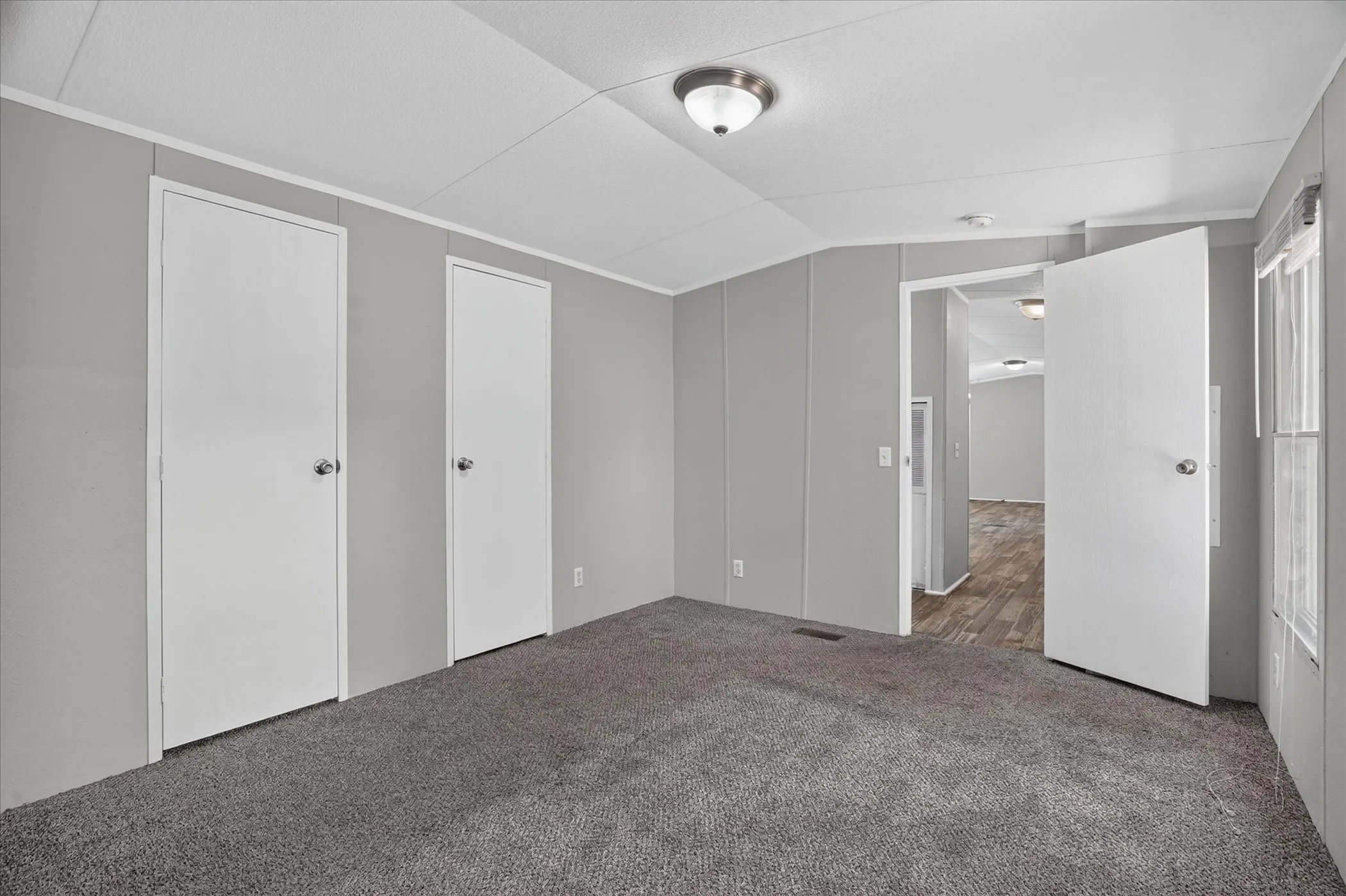 Carpeted flooring, paneled walls, flush mount lighting, and white interior doors