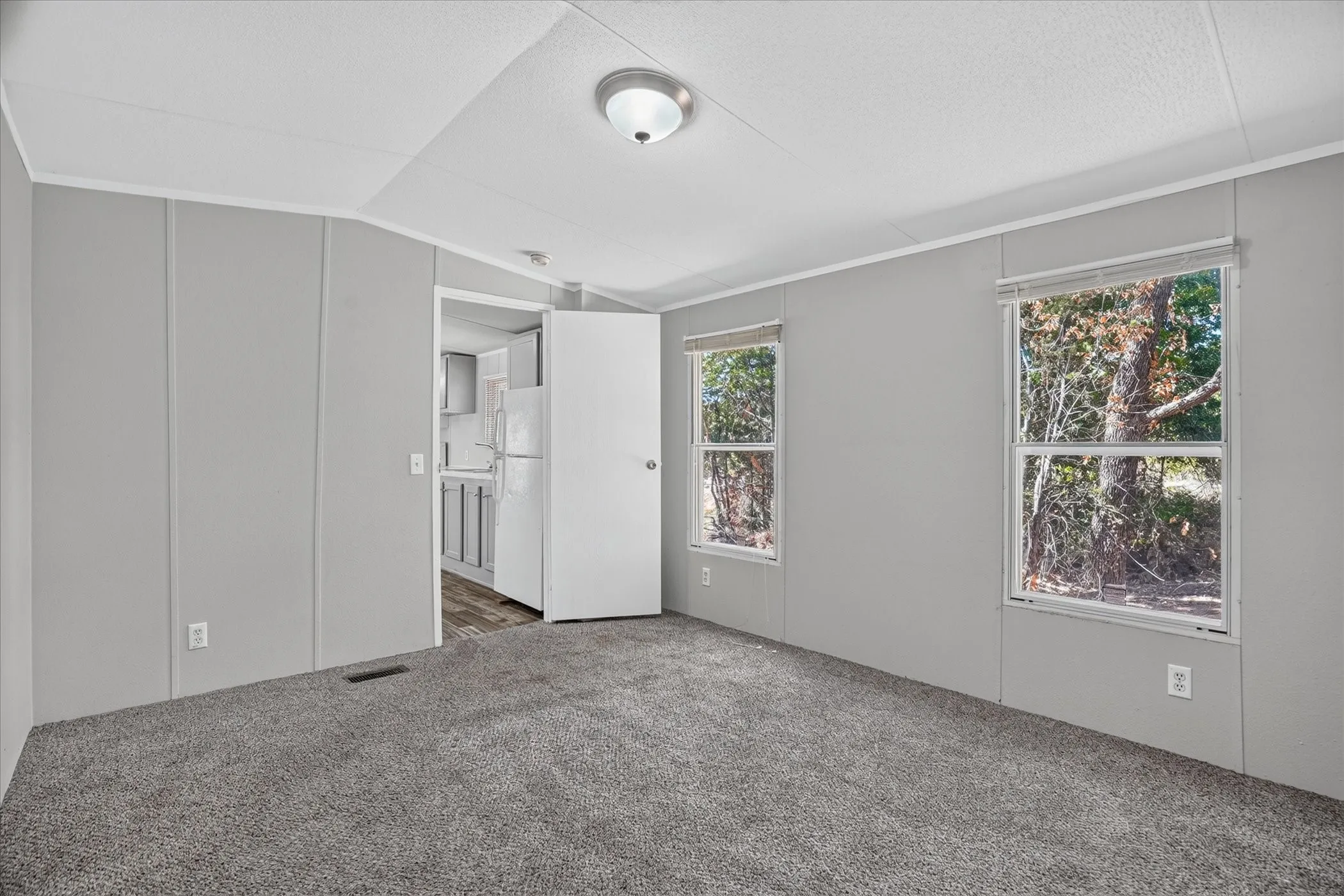 Bright bedroom featuring neutral wall finishes, carpeted flooring, and abundant natural light from dual windows