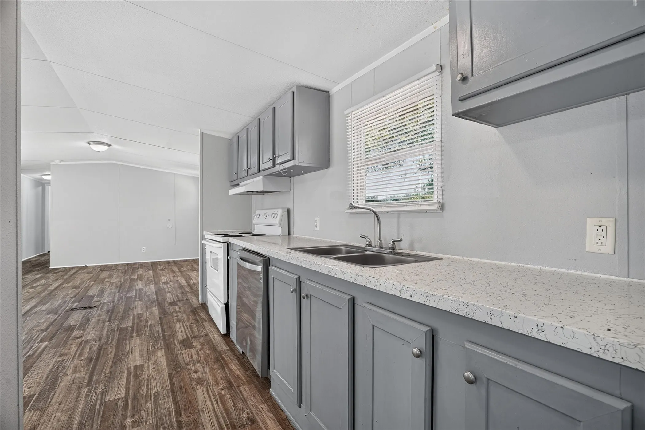 Kitchen featuring wood-finish flooring, gray cabinetry with silver hardware, and a double basin stainless steel sink